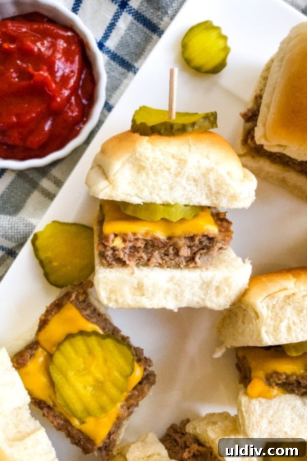 Ultimate Crowd-Pleasing Cheeseburger Sliders 16 Close-up of a single cheeseburger slider featuring a dill pickle chip, highlighting its deliciousness.