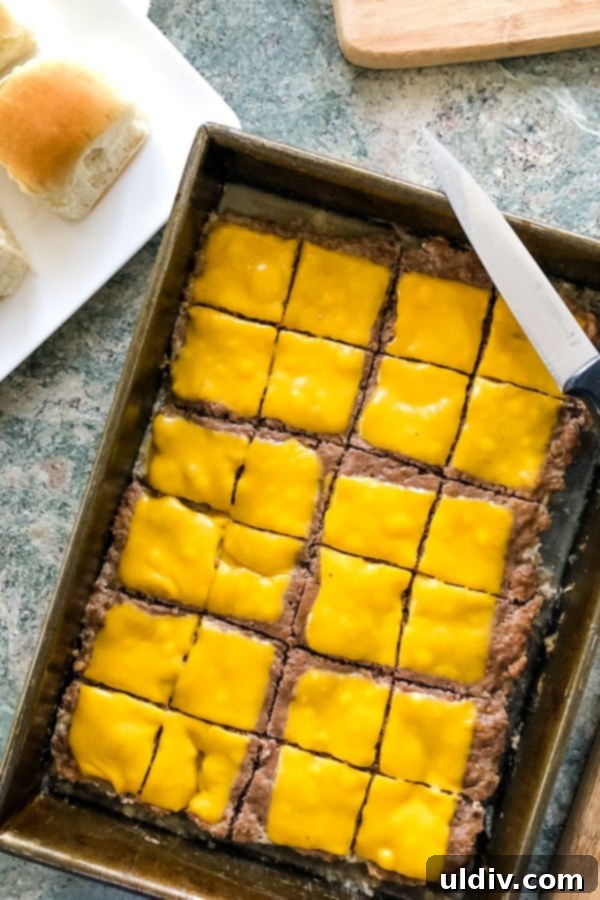 Ultimate Crowd-Pleasing Cheeseburger Sliders 19 Close-up shot of the large cheeseburger patty with melted cheese, ready to be cut into individual sliders.