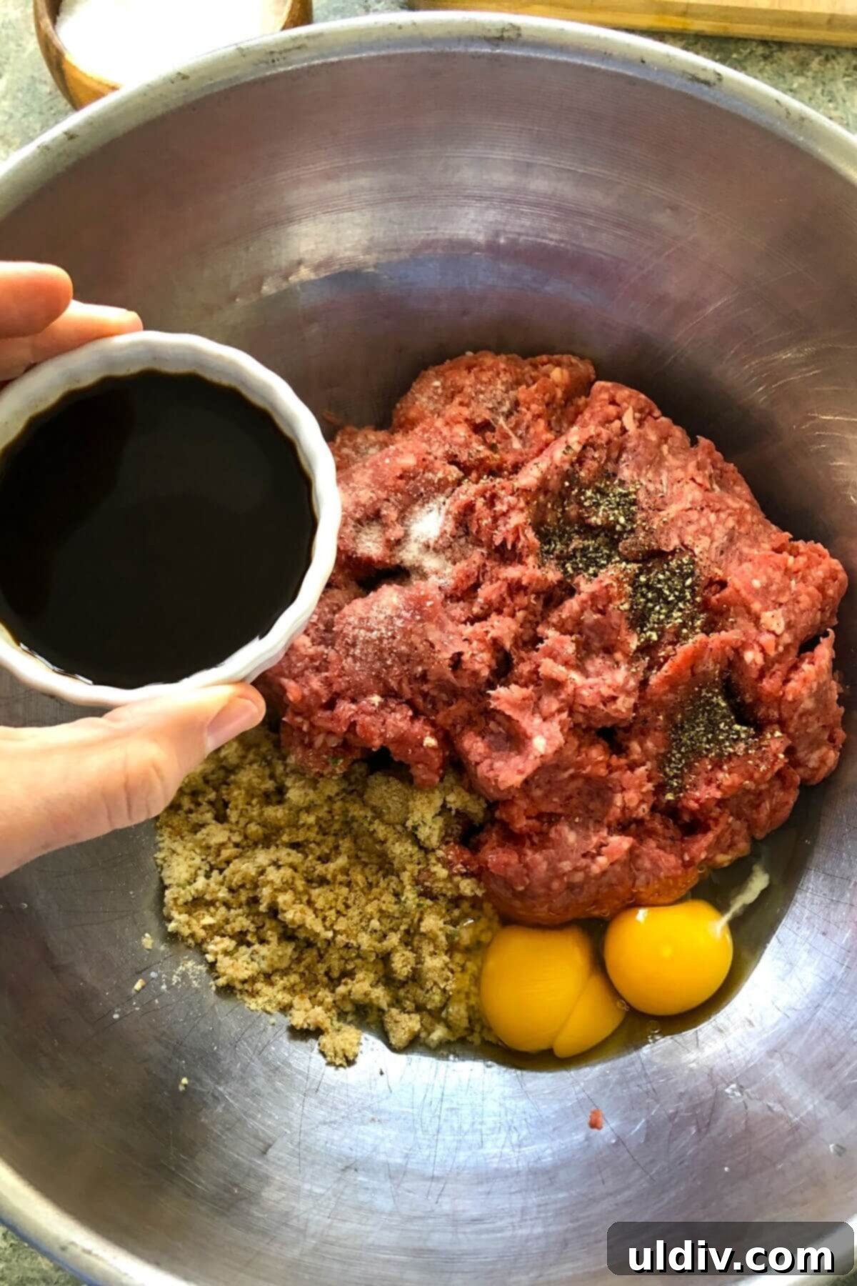 Ultimate Crowd-Pleasing Cheeseburger Sliders 6 A large bowl filled with ground beef, bread crumbs, eggs, and seasonings, being gently combined.