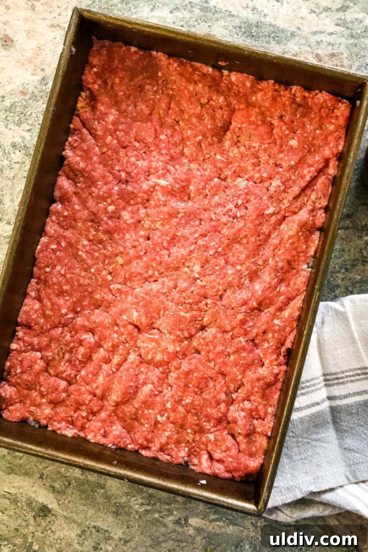 Crowd-Pleasing Cheeseburger Sliders 7 seasoned ground beef mixture pressed firmly and evenly into the baking pan, on top of the onions.