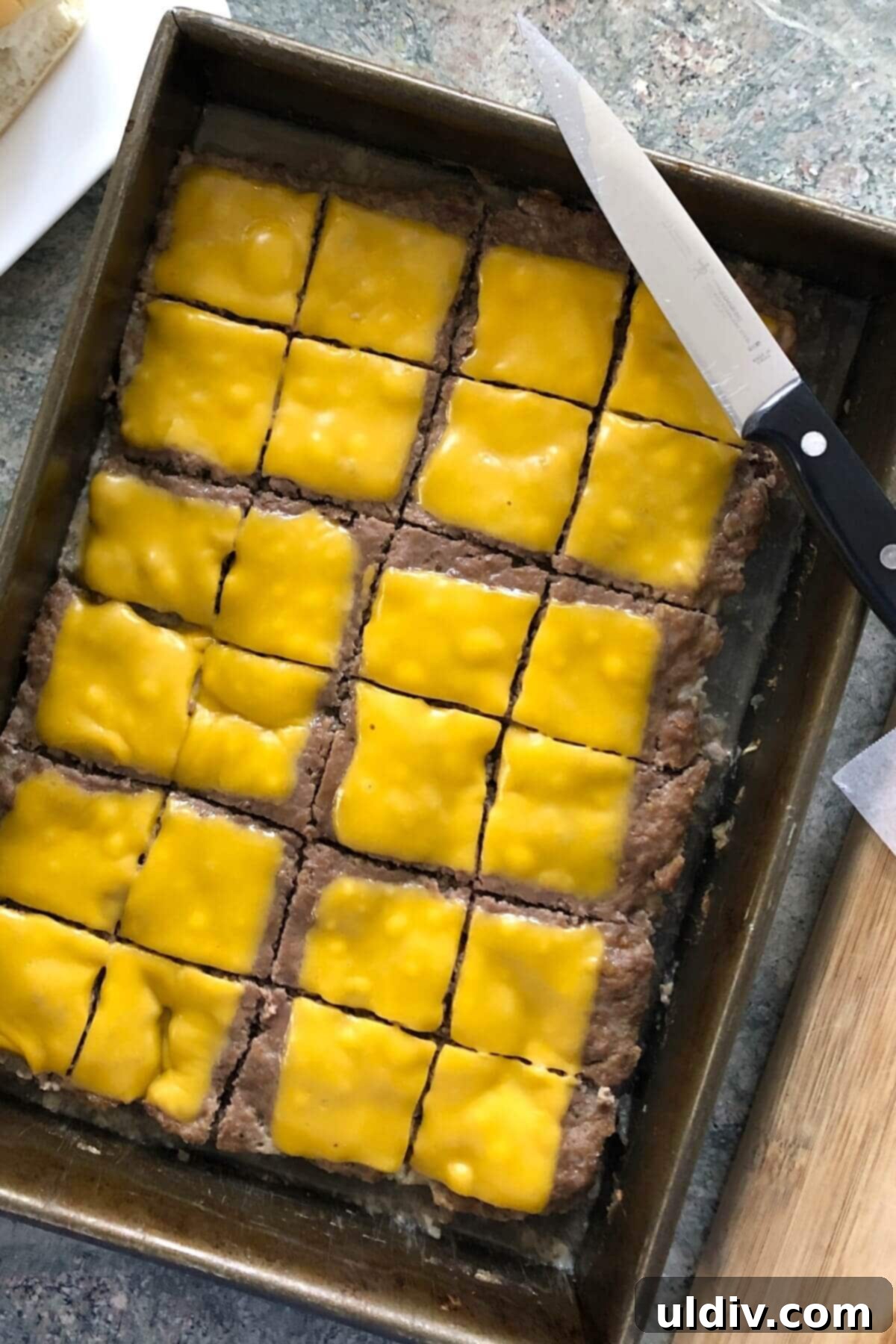 Ultimate Crowd-Pleasing Cheeseburger Sliders 9 A large burger patty, now fully cooked and topped with melted American cheese, ready to be cut into sliders.