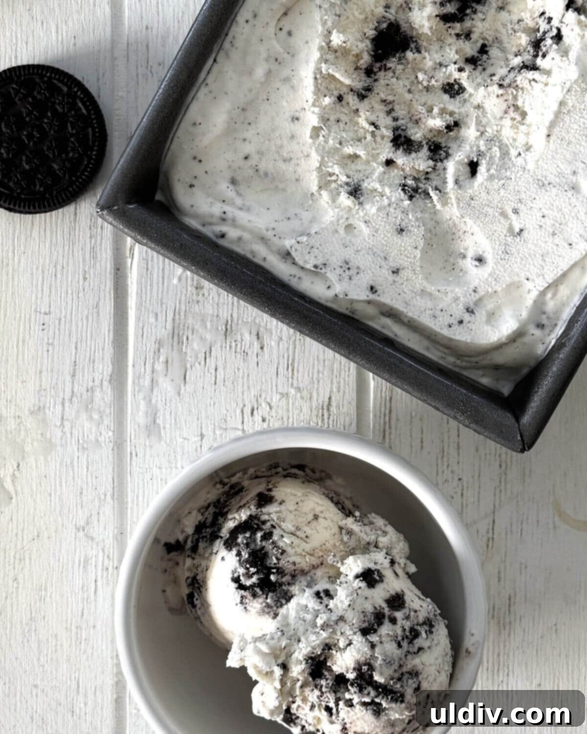 A bowl of cookies and cream ice cream next to a pan of freshly made no-churn ice cream.