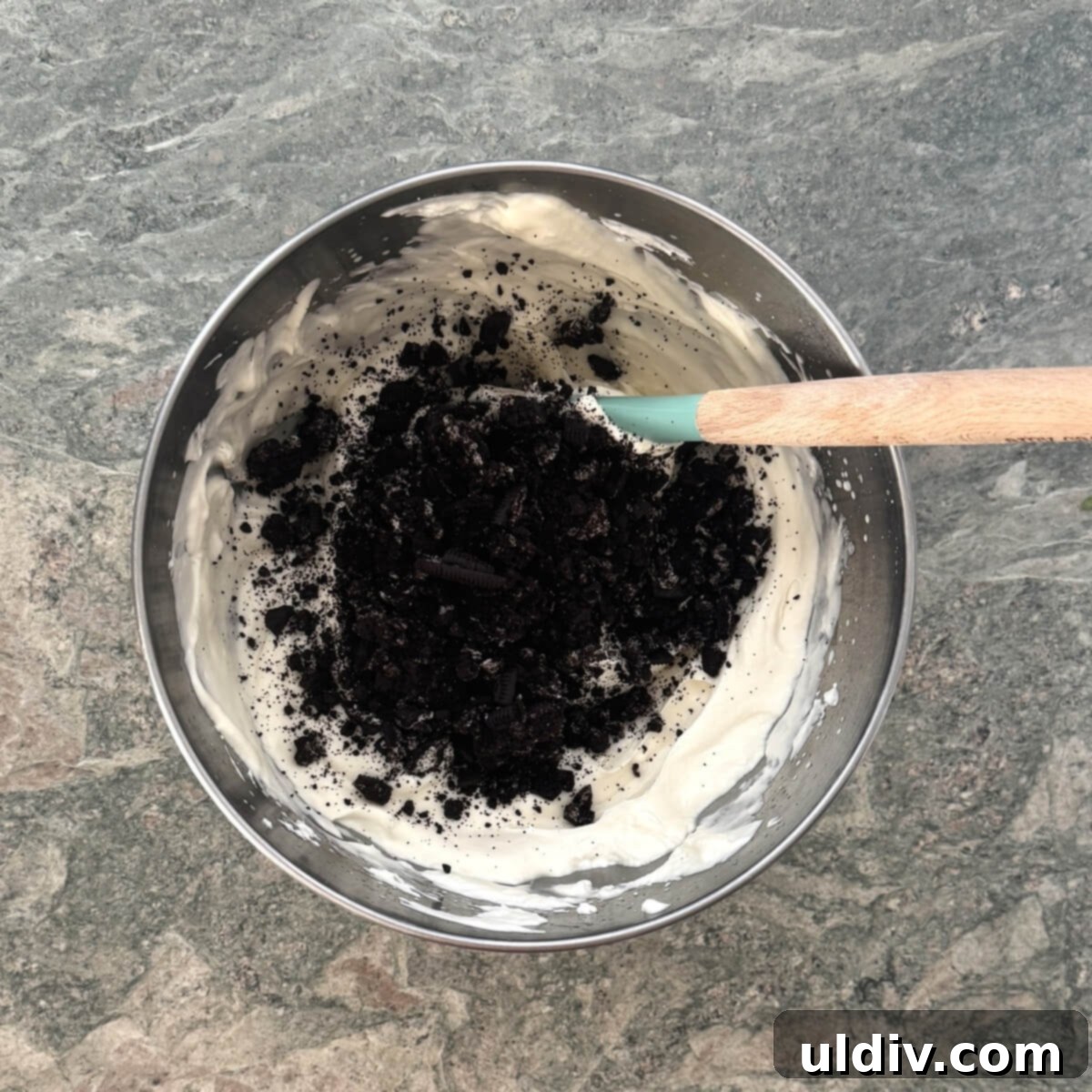 Crushed cookies being stirred into the ice cream mixture.
