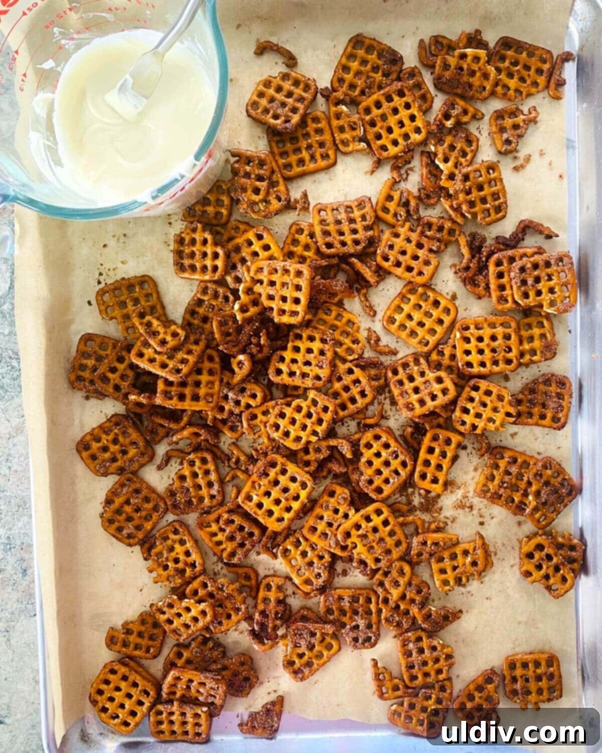 White Chocolate Glazed Pumpkin Spice Pretzels 8 Freshly baked pumpkin spiced pretzels, golden brown and coated, cooling on a baking sheet.