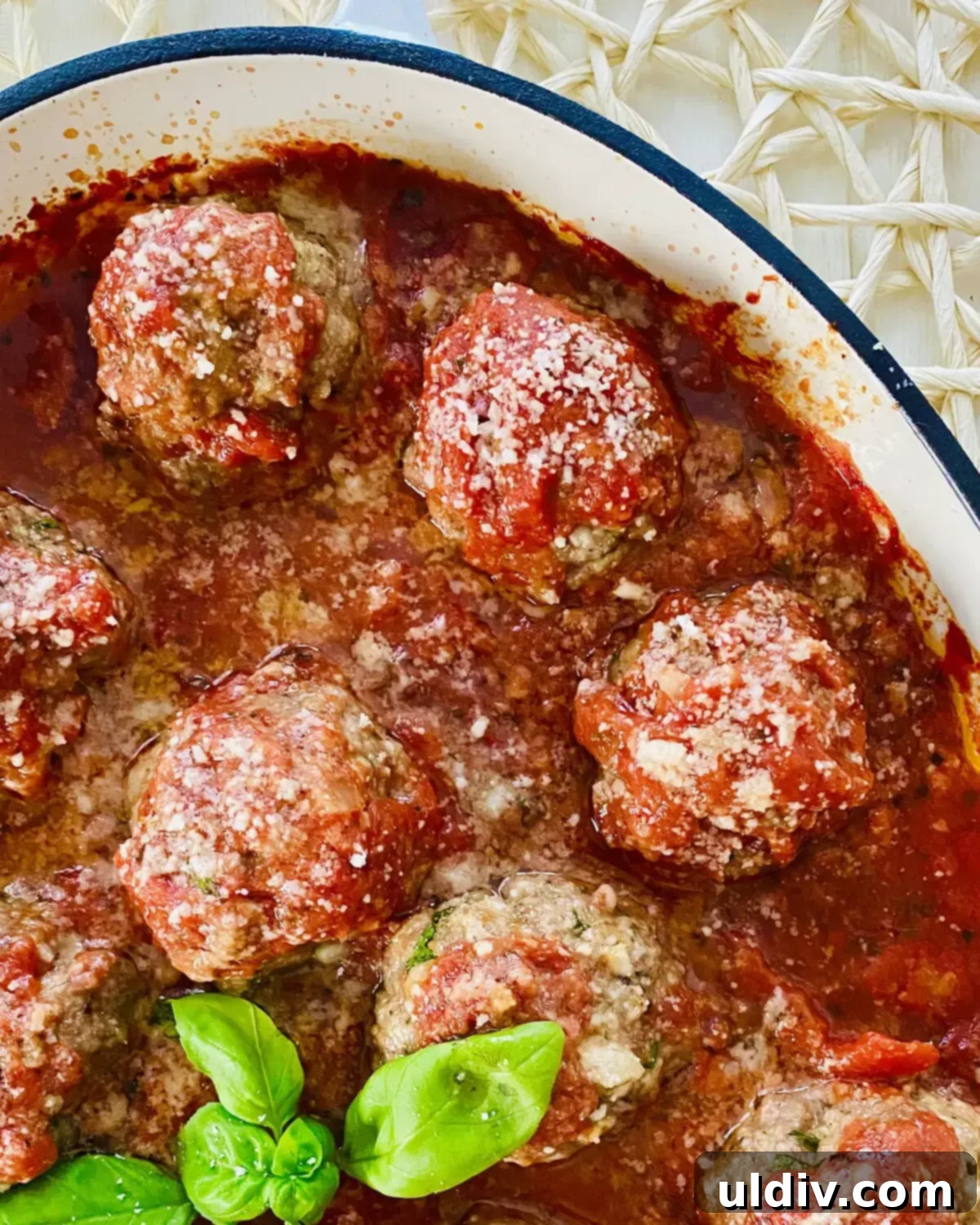 Close-up of tender Italian meatballs baked in a vibrant homemade marinara sauce, garnished with fresh herbs.