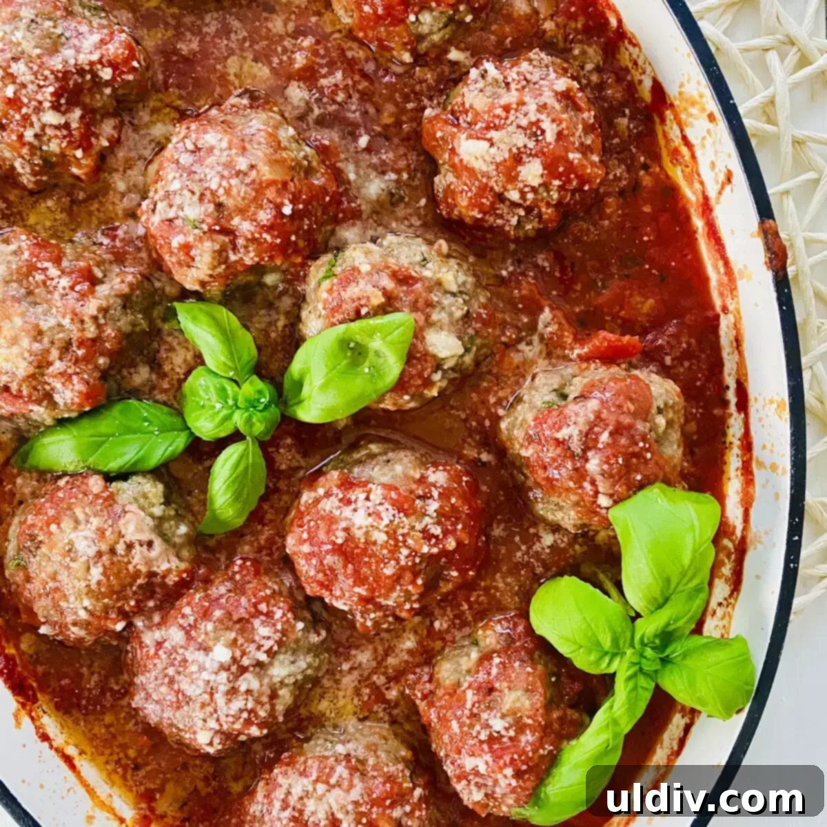 Oven-Kissed Meatballs in Rich Marinara 12 Tender Italian meatballs baking in rich marinara sauce in a white ceramic pan.