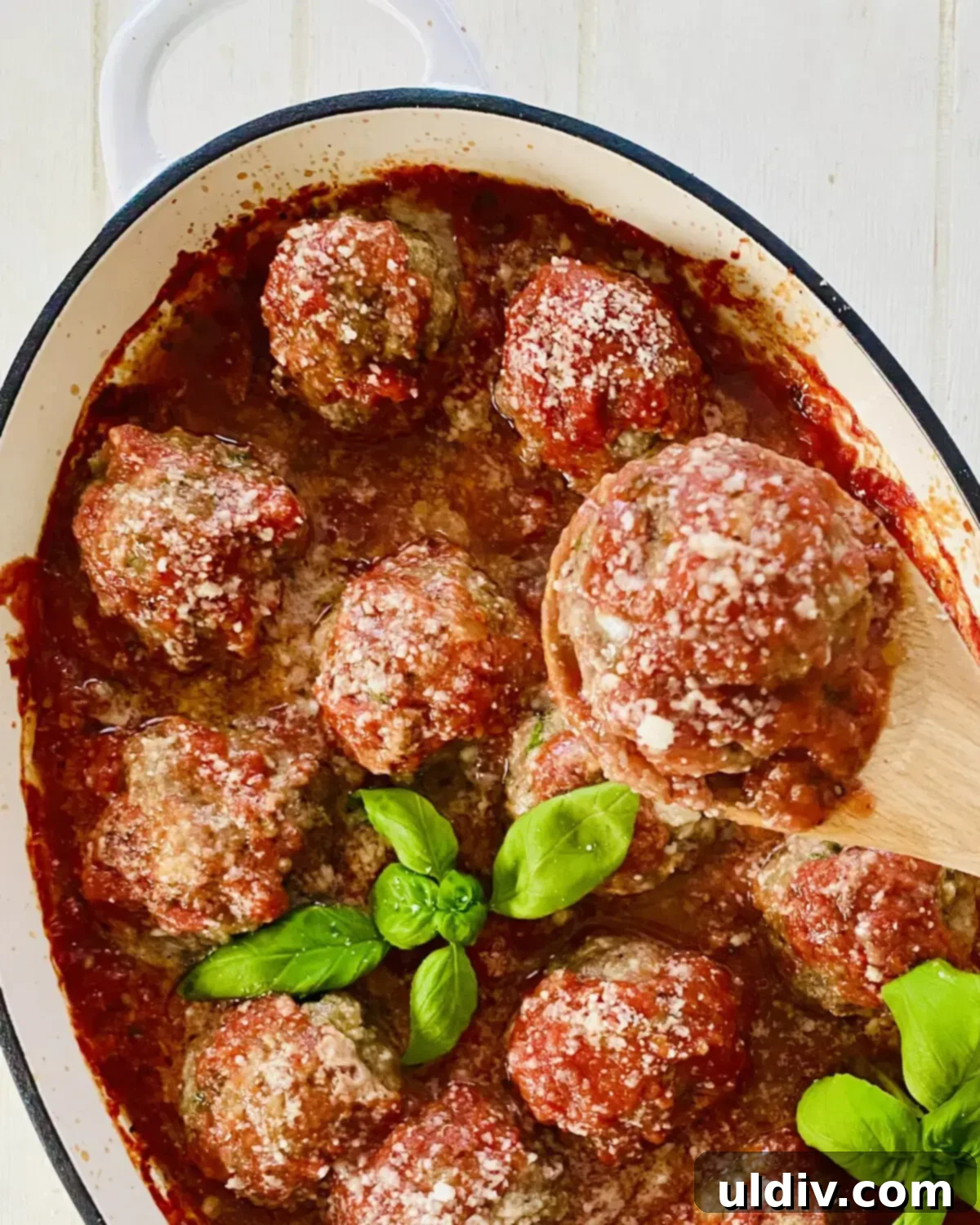 A spoonful of meatball marinara, showcasing a tender meatball coated in rich red sauce, ready to be tasted.