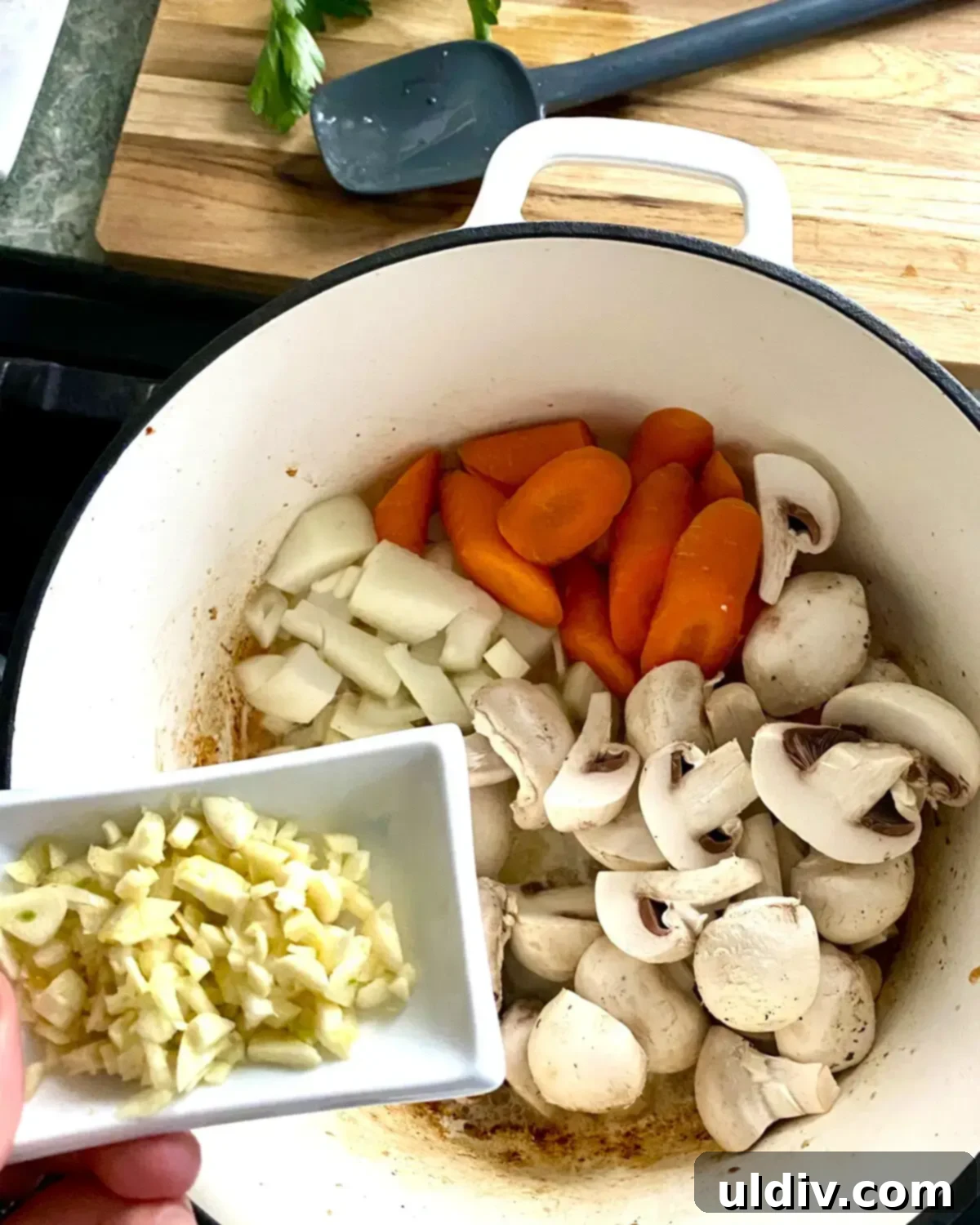 Smoky Pork Tenderloin and Bacon Stew 6 A dish of chopped garlic and a pot with sliced onion, mushrooms and carrots.