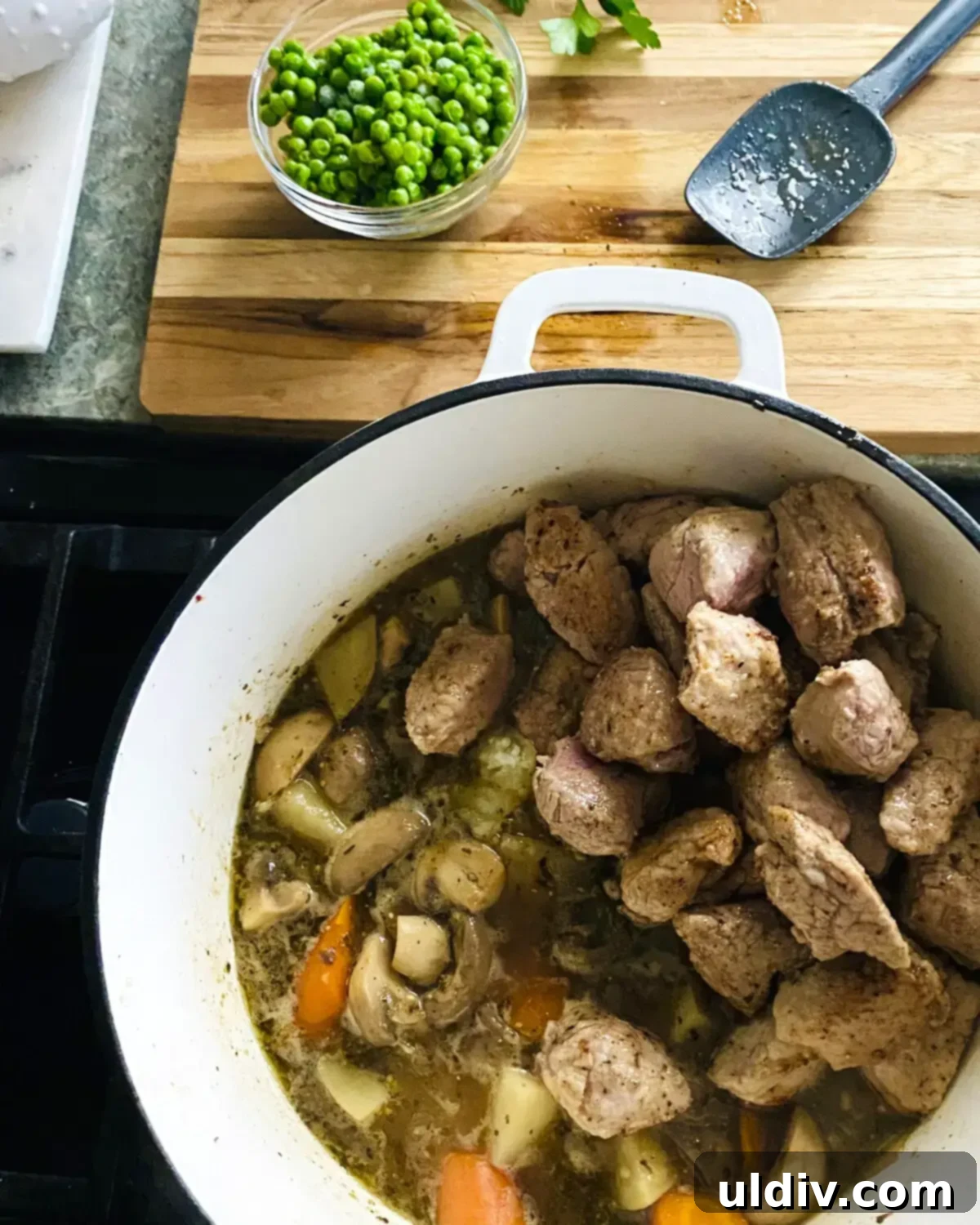 Hearty Pork Tenderloin and Bacon Stew 10 Pork tenderloin cubes and green peas added to the pot with cooked vegetables and simmering stew.