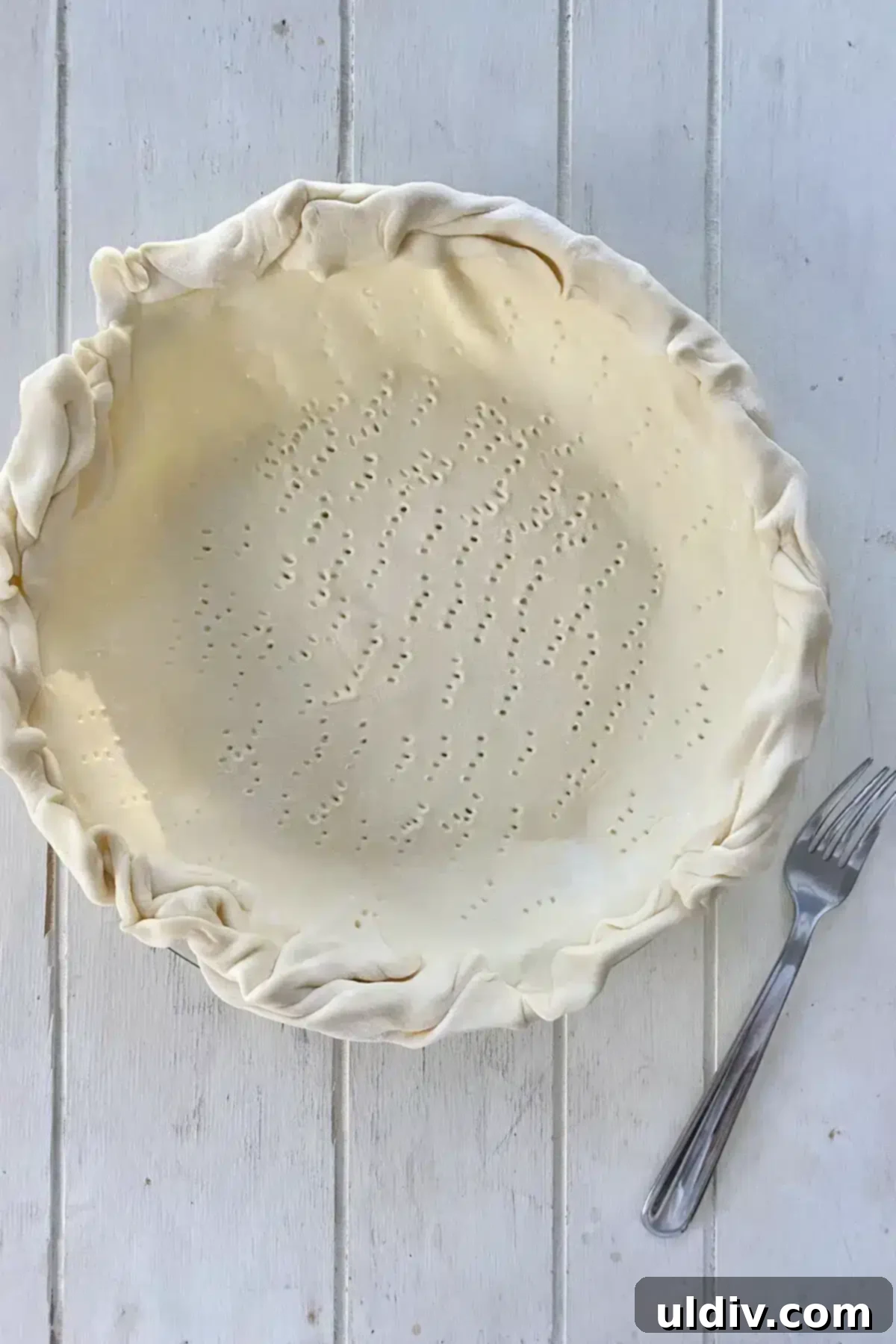Flaky Puff Pastry Mushroom Quiche 4 Unbaked puff pastry crust expertly placed in a pie plate with crimped edges and fork pricks.