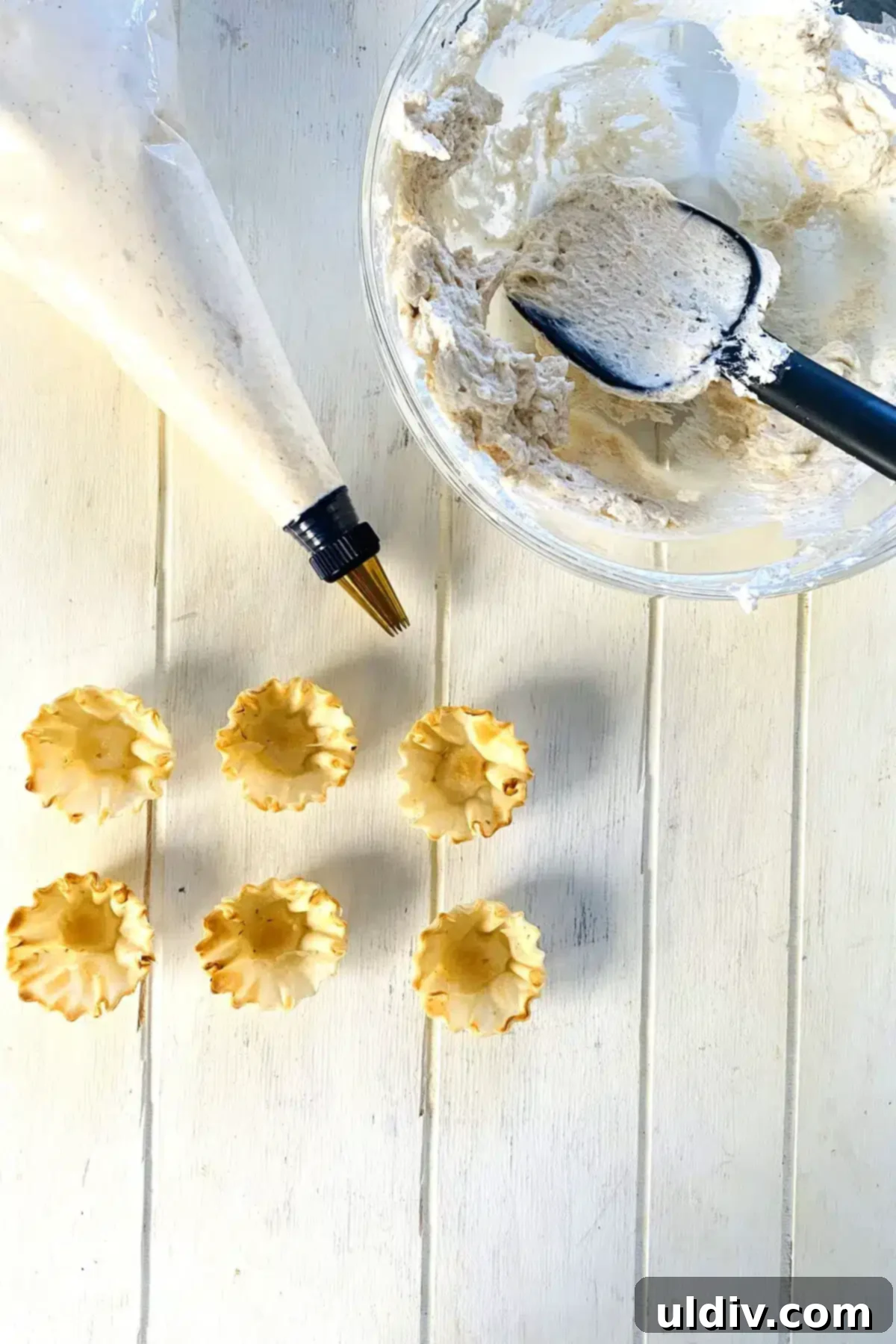 Simple Philadelphia No-Bake Cheesecake Bites 8 Piping bag filled with cheesecake filling and empty phyllo cups.
