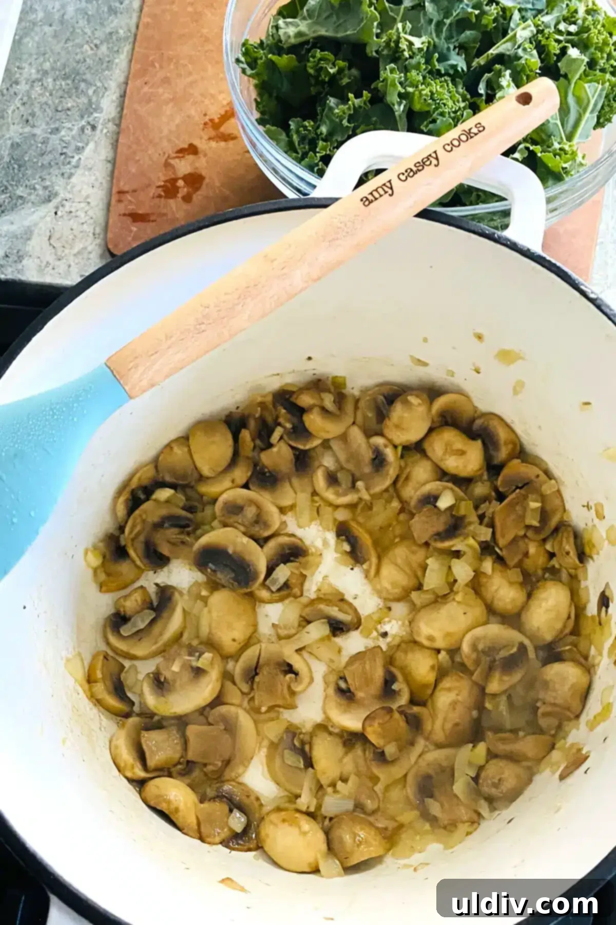 Comforting Creamy Chicken and Kale Casserole 5 Sautéed mushrooms, onions, and garlic gently cooking in a white Dutch oven, creating an aromatic base.