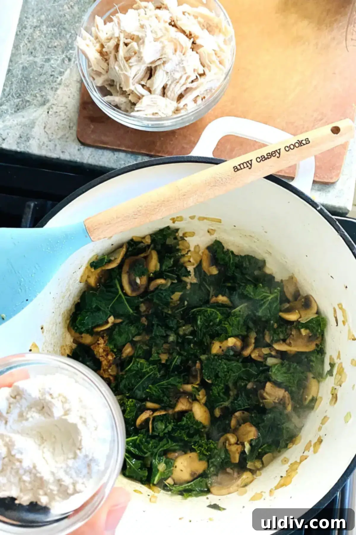Comforting Creamy Chicken and Kale Casserole 7 Flour being sprinkled over the sautéed vegetables, forming the base for the rich sauce.