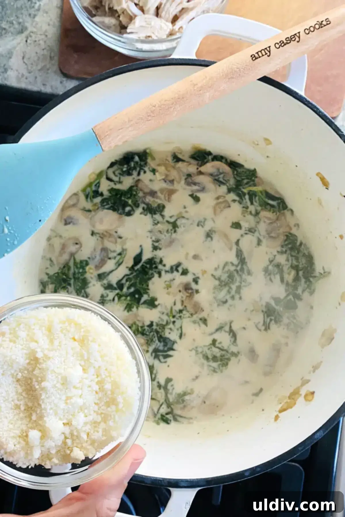 Comforting Creamy Chicken and Kale Casserole 9 Grated Parmesan cheese being stirred into the luscious kale cream sauce, adding richness.