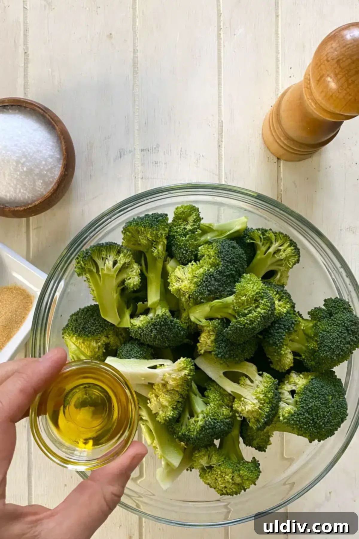 Golden Garlic Crispy Broccoli 5 raw broccoli florets in a glass bowl and adding olive oil.