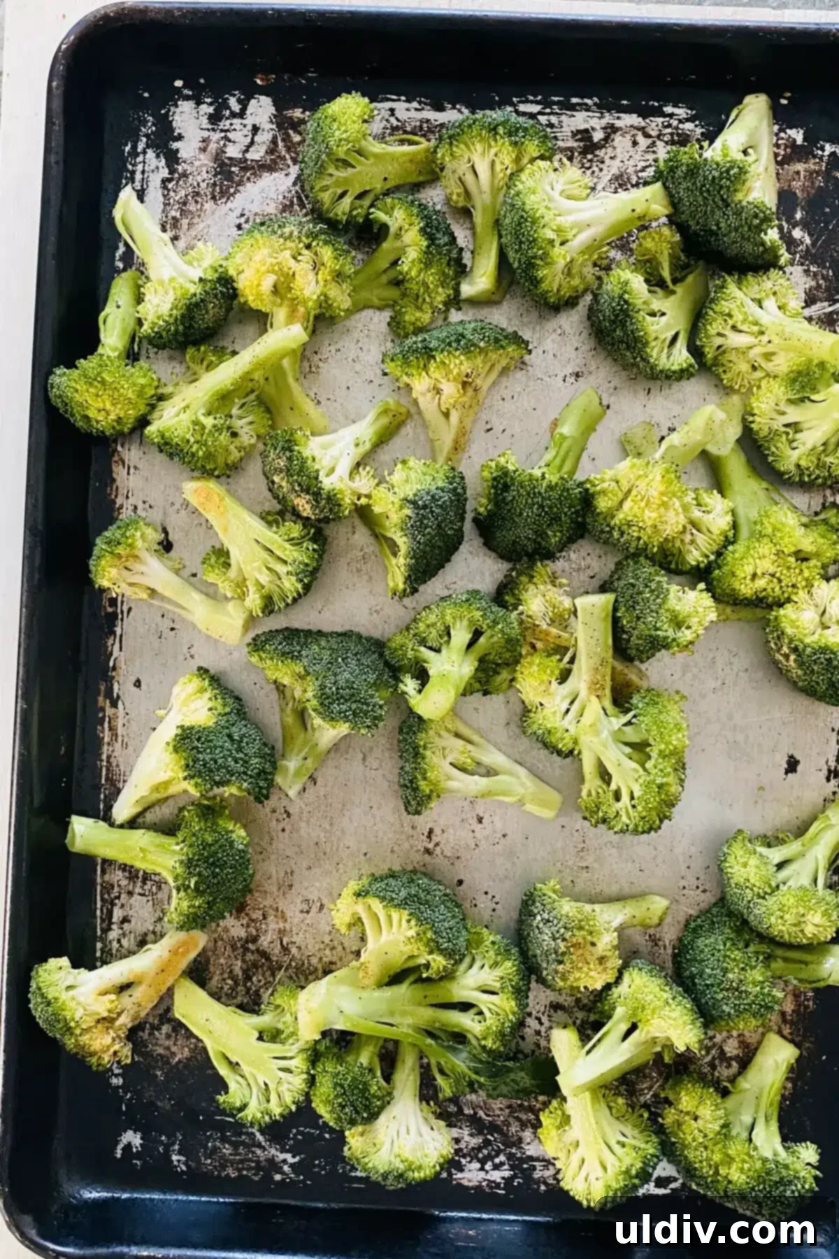 Golden Garlic Roasted Broccoli 9 Seasoned raw broccoli spread in a single layer on a preheated baking sheet.
