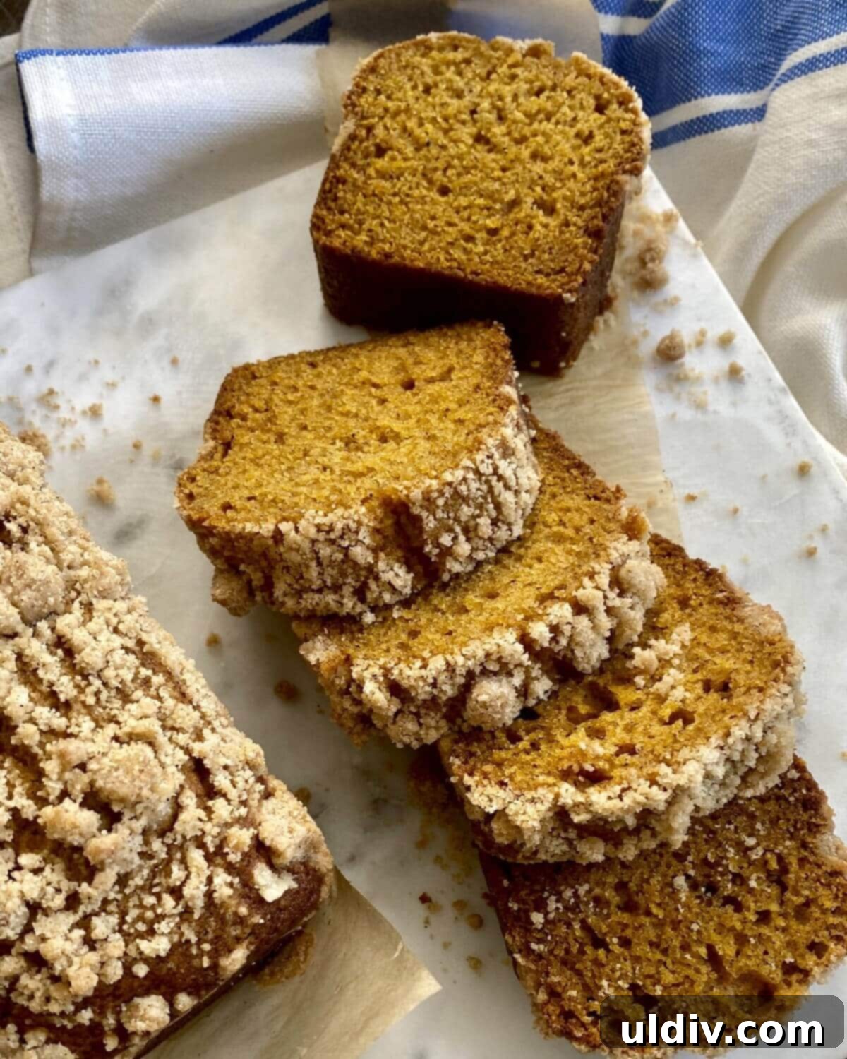 Cozy Autumn Mini Pumpkin Loaves 2 Mini pumpkin bread loaves, beautifully sliced and arranged on a elegant marble board, showcasing the moist interior and crumbly streusel topping.