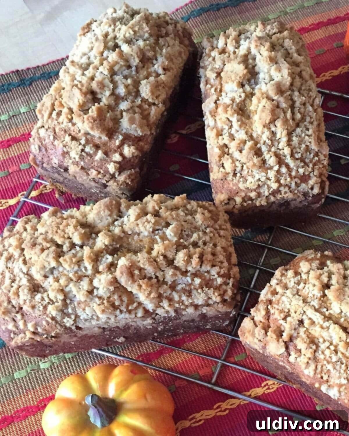 Delicious Mini Pumpkin Loaves 8 Four perfectly baked mini pumpkin loaves, golden brown and topped with streusel, cooling on a rack.