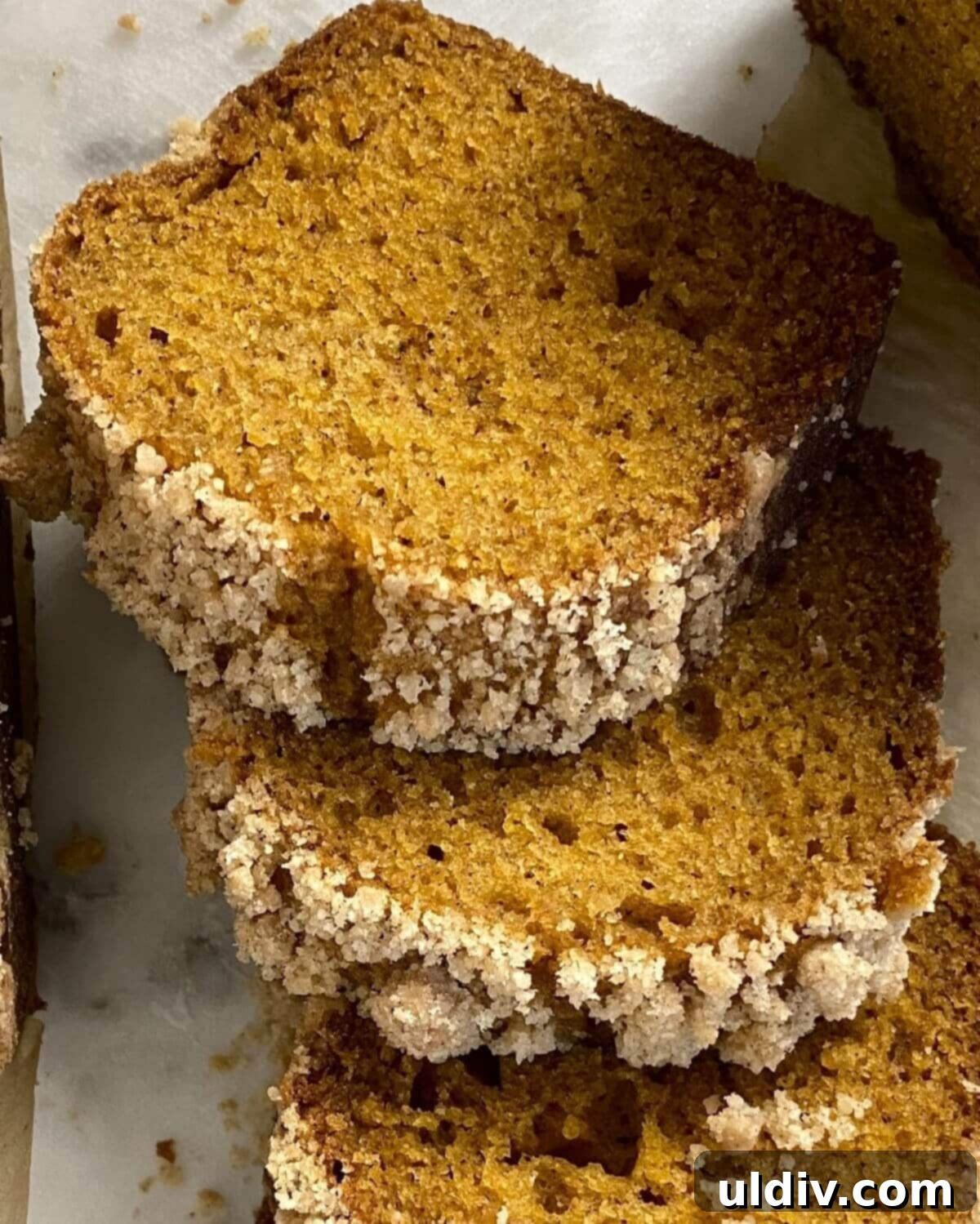 Cozy Autumn Mini Pumpkin Loaves 9 Three perfectly cut slices of moist mini pumpkin bread with streusel topping, arranged on a rustic plate.