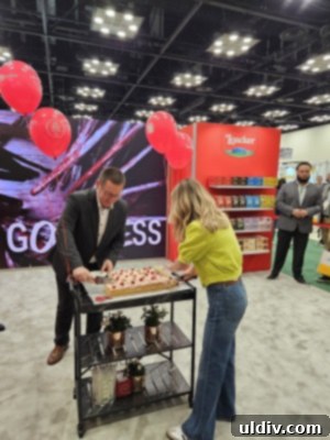 Unwrapping the 2025 Sweets & Snacks Expo 28 Chef Giada De Laurentiis posing next to a beautifully crafted cake made with Loacker raspberry-yogurt wafers.