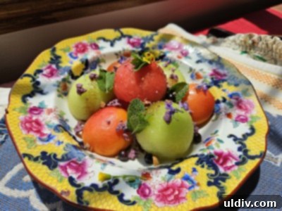 Melon Magic for Solstice 2025 4 A colorful and artfully arranged fruit salad on a plate, topped with blackcurrants and almonds.