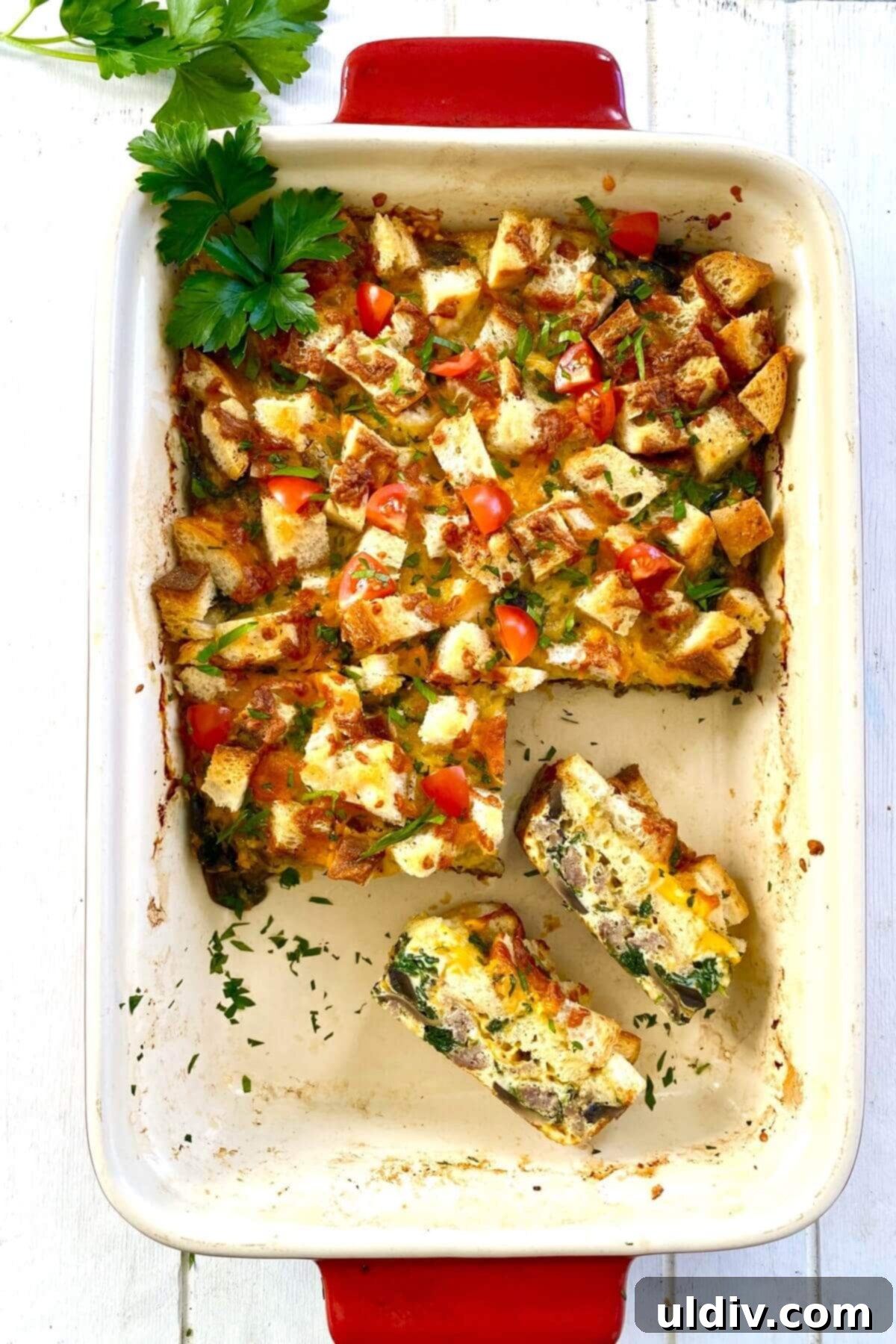 Sausage, Mushroom & Spinach Breakfast Strata 15 A baked egg casserole with two pieces cut out, revealing the fluffy interior and crispy crouton topping.