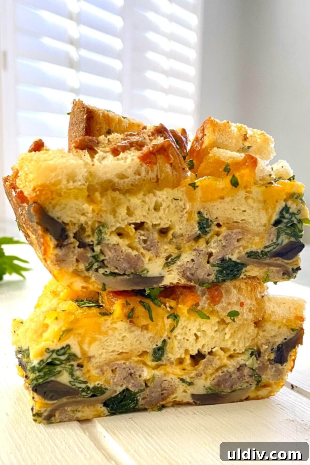 Loaded Breakfast Egg Bake with Sausage, Spinach, Mushrooms, and Croutons 3 2 slices of egg casserole with croutons stacked on top of each other.