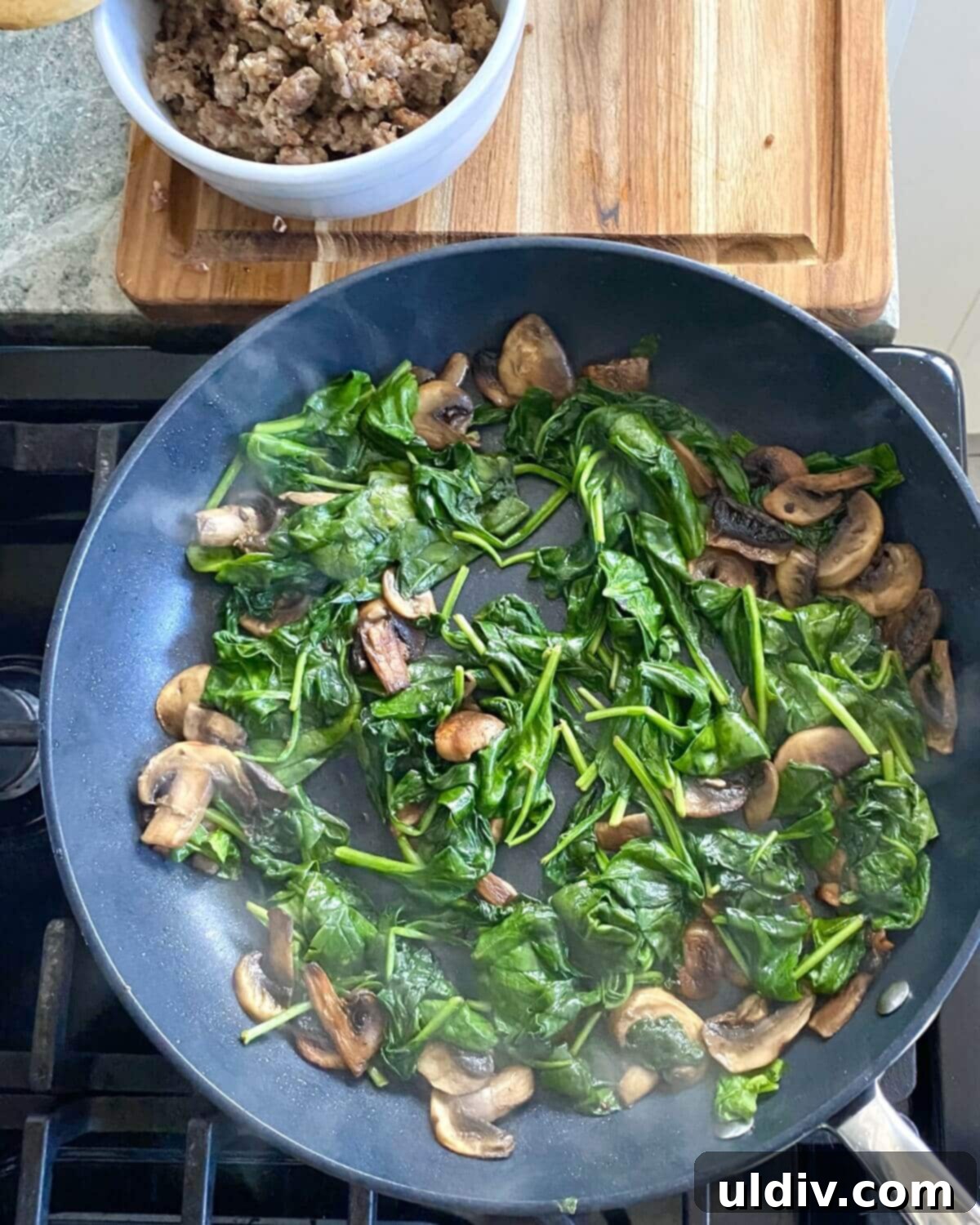 Sausage, Mushroom & Spinach Breakfast Strata 7 Sautéed mushrooms and wilted spinach in a pan, colorful and fragrant.