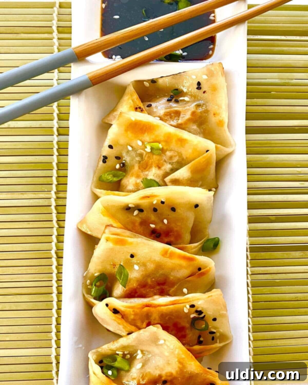 Crispy Pork Potstickers with Zesty Dipping Sauce 12 Pork potstickers on plate with chopsticks.