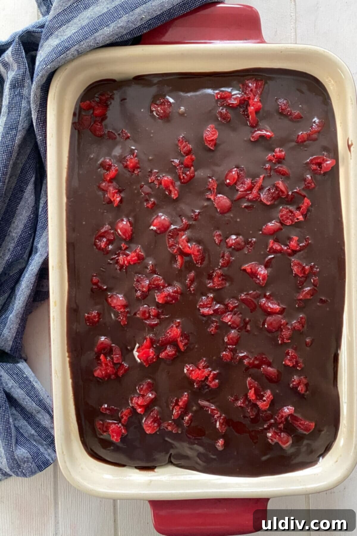 The finished Chocolate Cherry Cake, beautifully iced and garnished with vibrant chopped maraschino cherries, ready to be sliced and served.