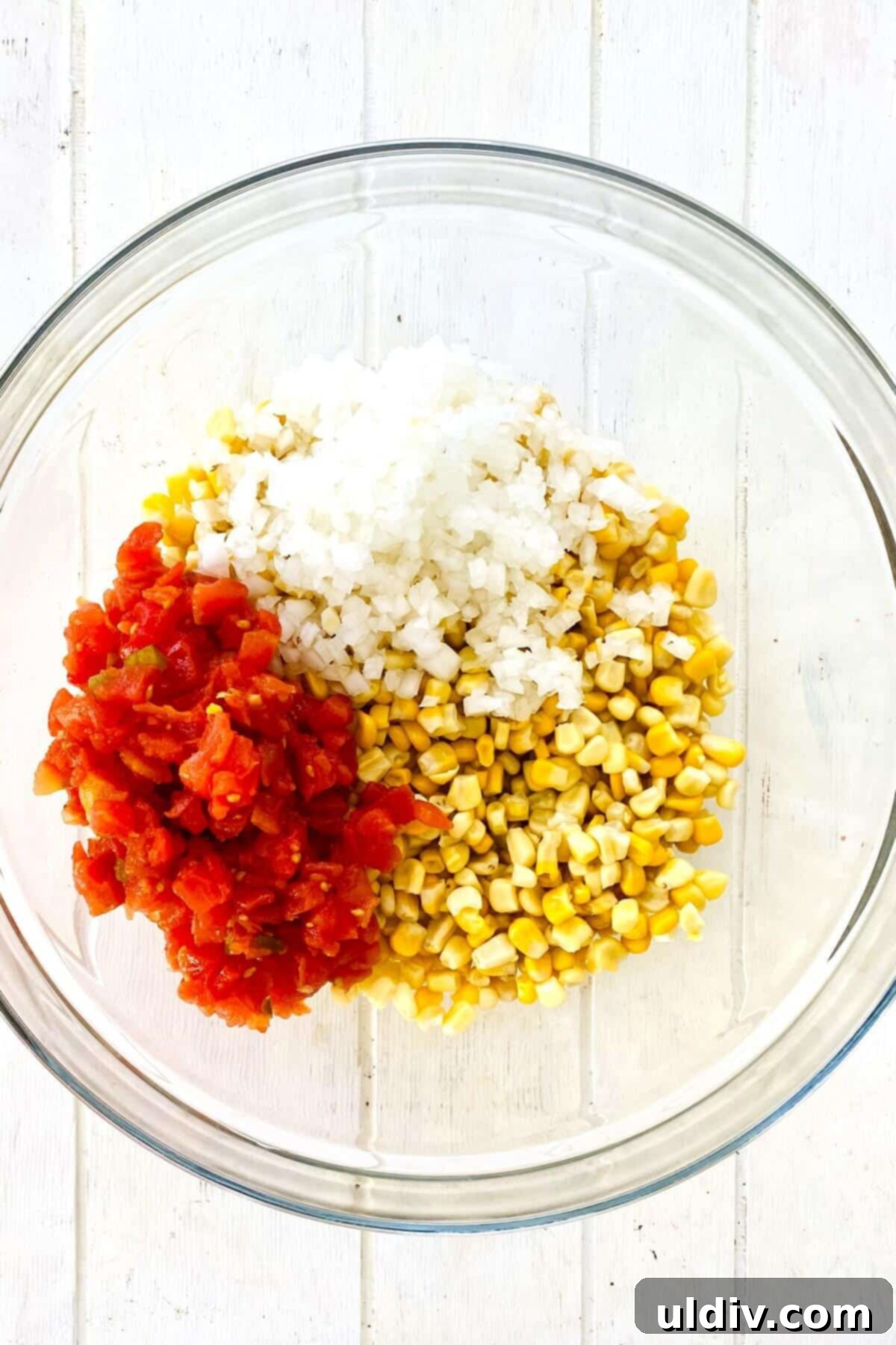 Baked Cheesy Corn Delight 5 corn, onion, rotel tomatoes in a bowl.