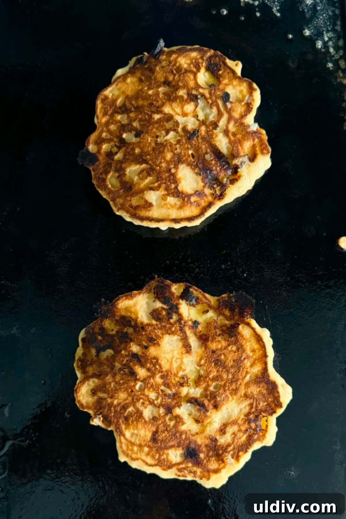 Wholesome Banana Cottage Cheese Protein Pancakes 11 Perfectly cooked golden-brown banana protein pancakes flipped on a griddle, ready to finish cooking.