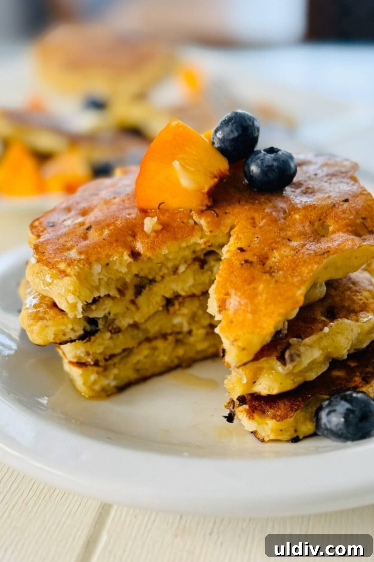 Power-Packed Banana Cottage Cheese Protein Pancakes 14 A stack of golden-brown protein pancakes with a bite taken out of one, showcasing their fluffy interior.