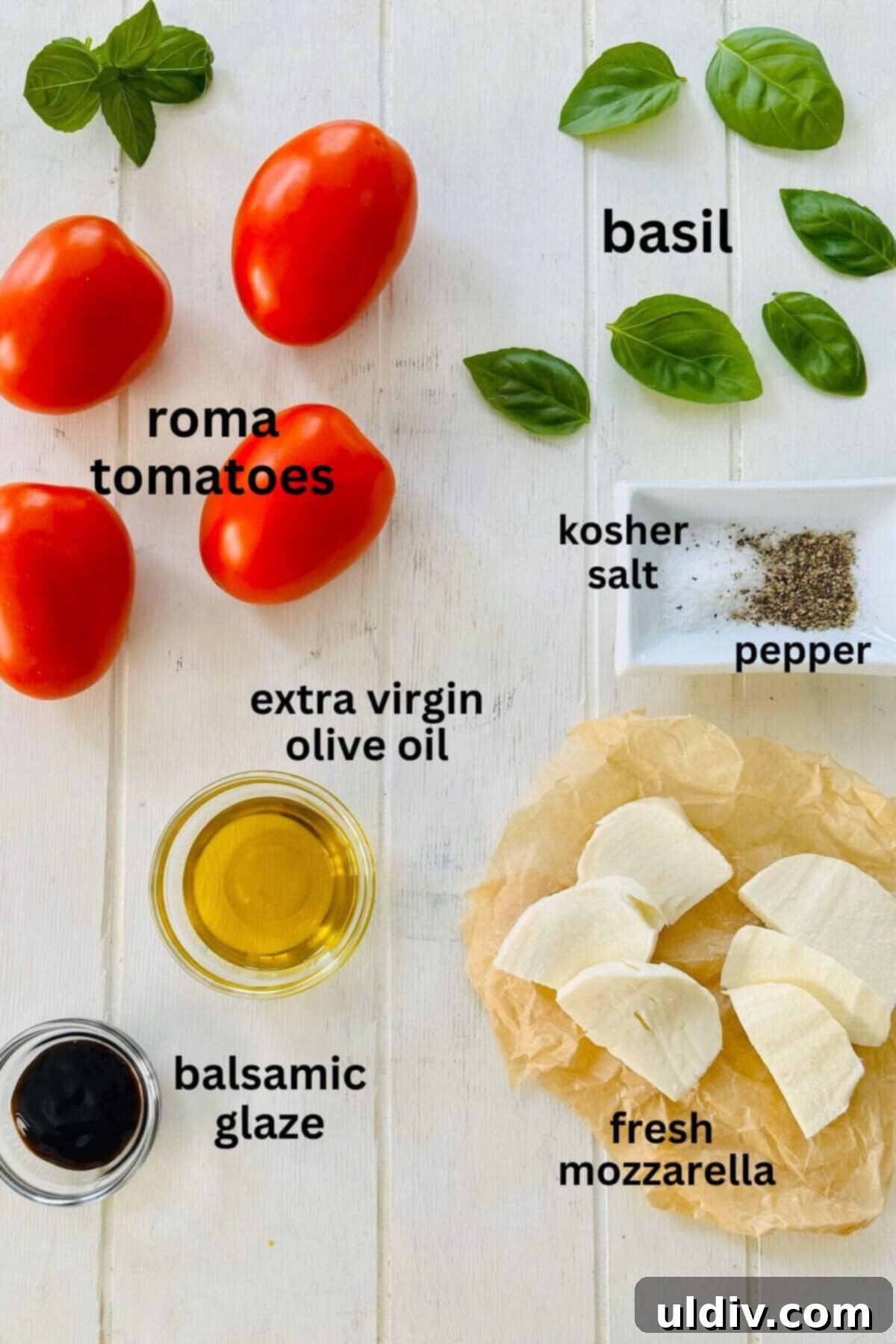 Stuffed Tomato Caprese Salad 3 A flat lay of fresh ingredients for Stuffed Caprese Salad: whole Roma tomatoes, fresh mozzarella balls, vibrant basil leaves, a bottle of olive oil, a bottle of balsamic glaze, a salt shaker, and a pepper mill.