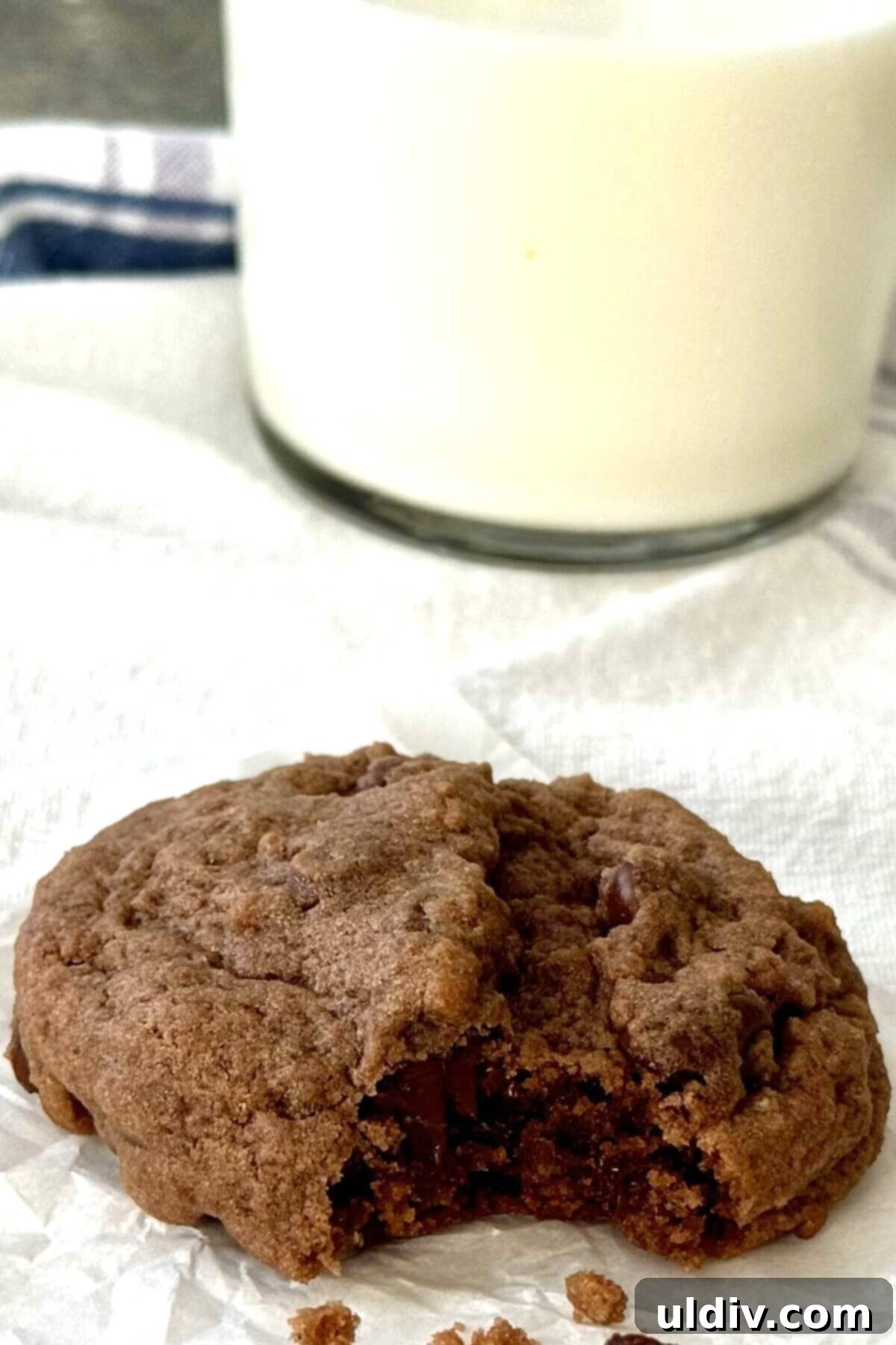 Double Chocolate Pudding Cookies 3 A chocolate cookie with a bite taken out, resting next to a refreshing glass of milk.