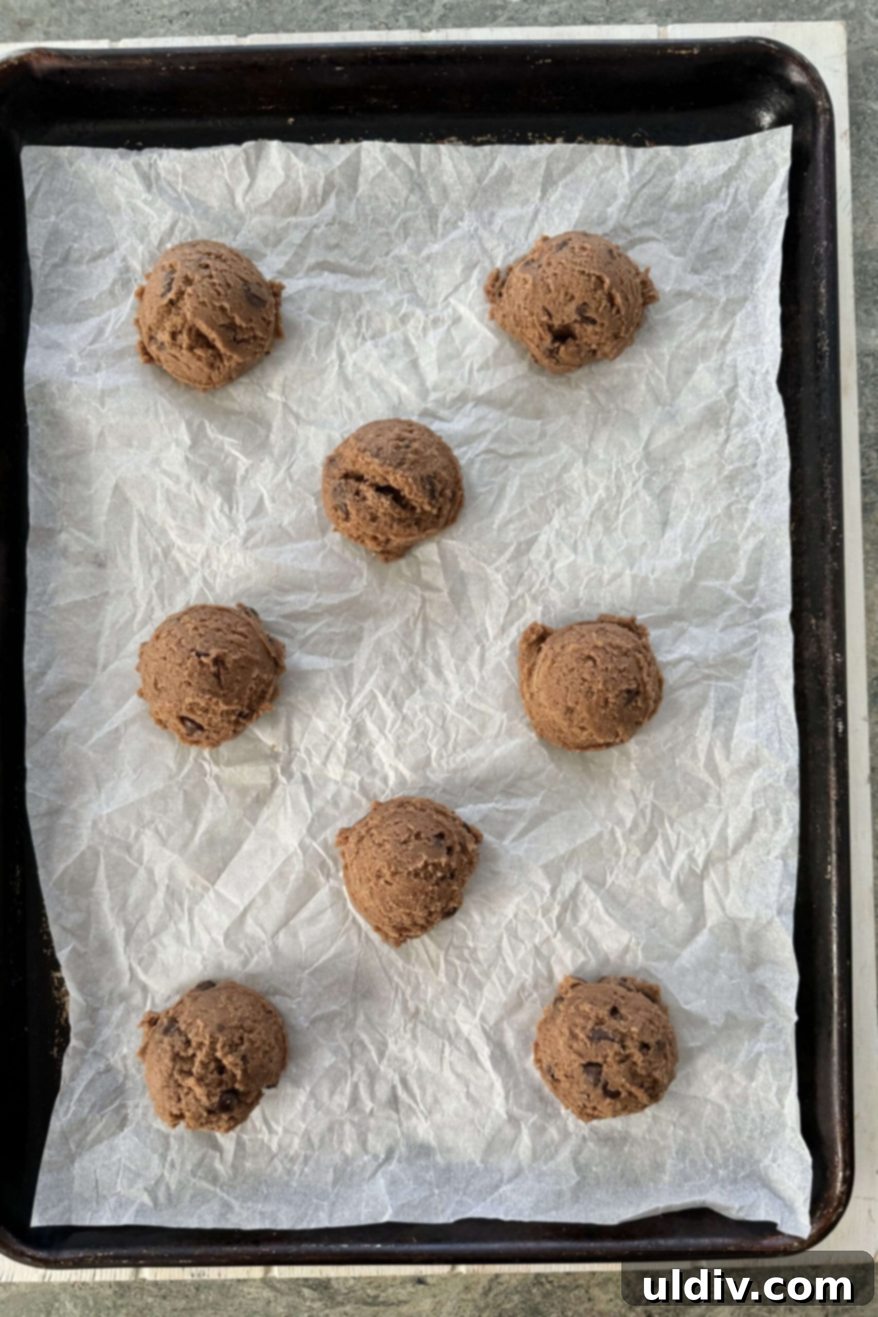 Double Chocolate Pudding Cookies 10 Raw chocolate cookie dough balls neatly arranged on a parchment paper-lined baking sheet.