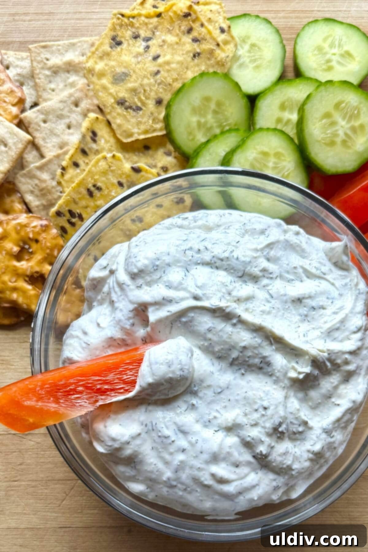 Easy 5-Minute Dill Dip 2 A bowl of dill dip with a bell pepper dipped in it, highlighting its creamy texture and vibrant green specks of dill.