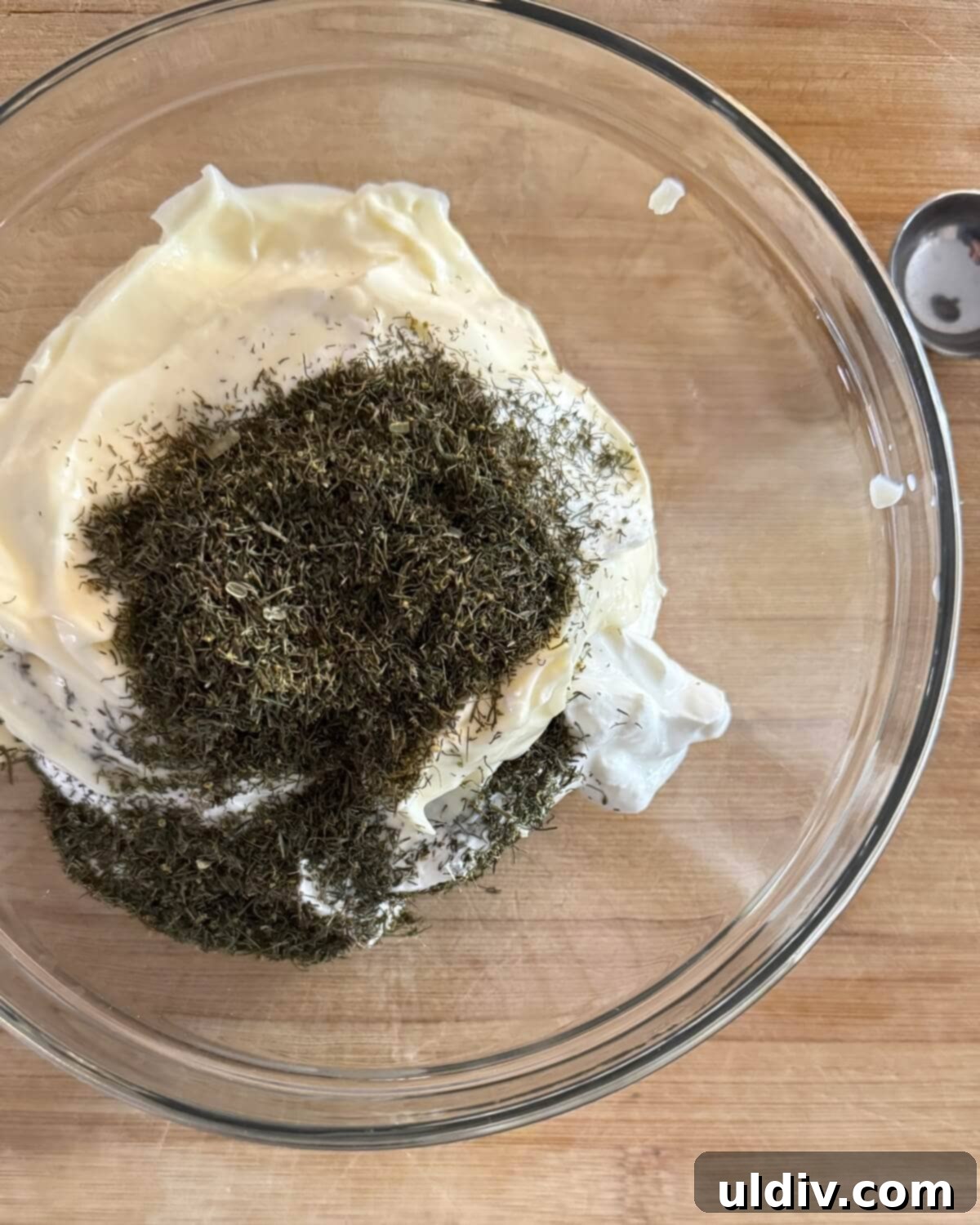 Fresh Dill Dip in Minutes 6 Dried dill sprinkled over the combined mayonnaise and sour cream in a clear glass bowl, adding the signature herb.