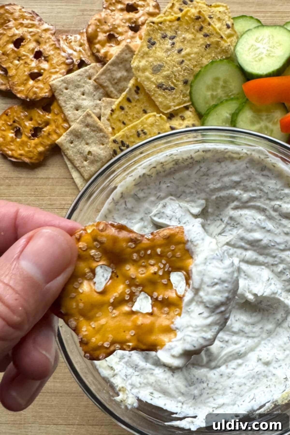 Easy 5-Minute Dill Dip 9 A crispy pretzel thin delicately dipped into a bowl of creamy homemade dill dip, highlighting a perfect snack pairing.