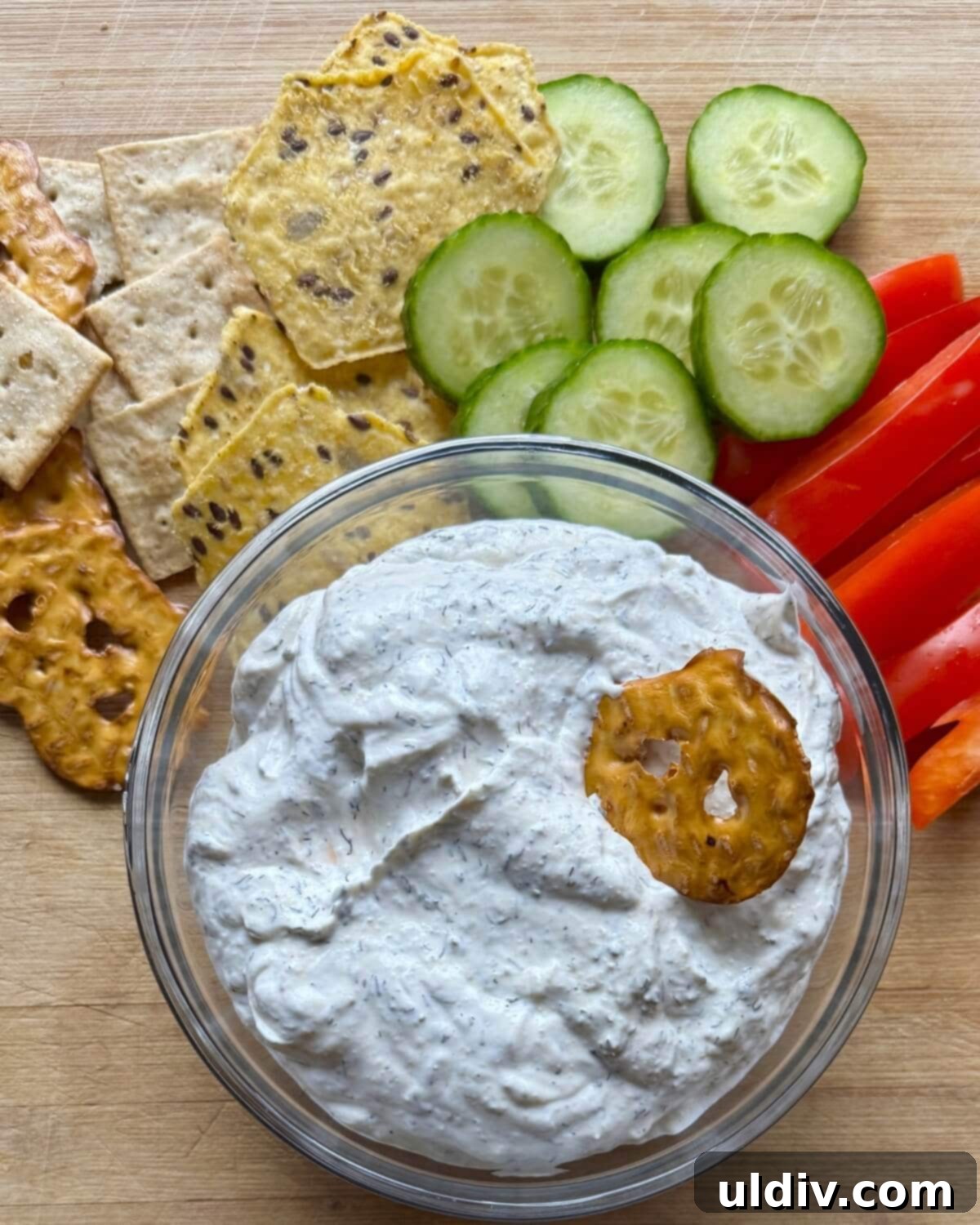 Easy 5-Minute Dill Dip 10 A pretzel being dipped into a bowl of creamy sour cream and dill dip, ready for a delightful bite.