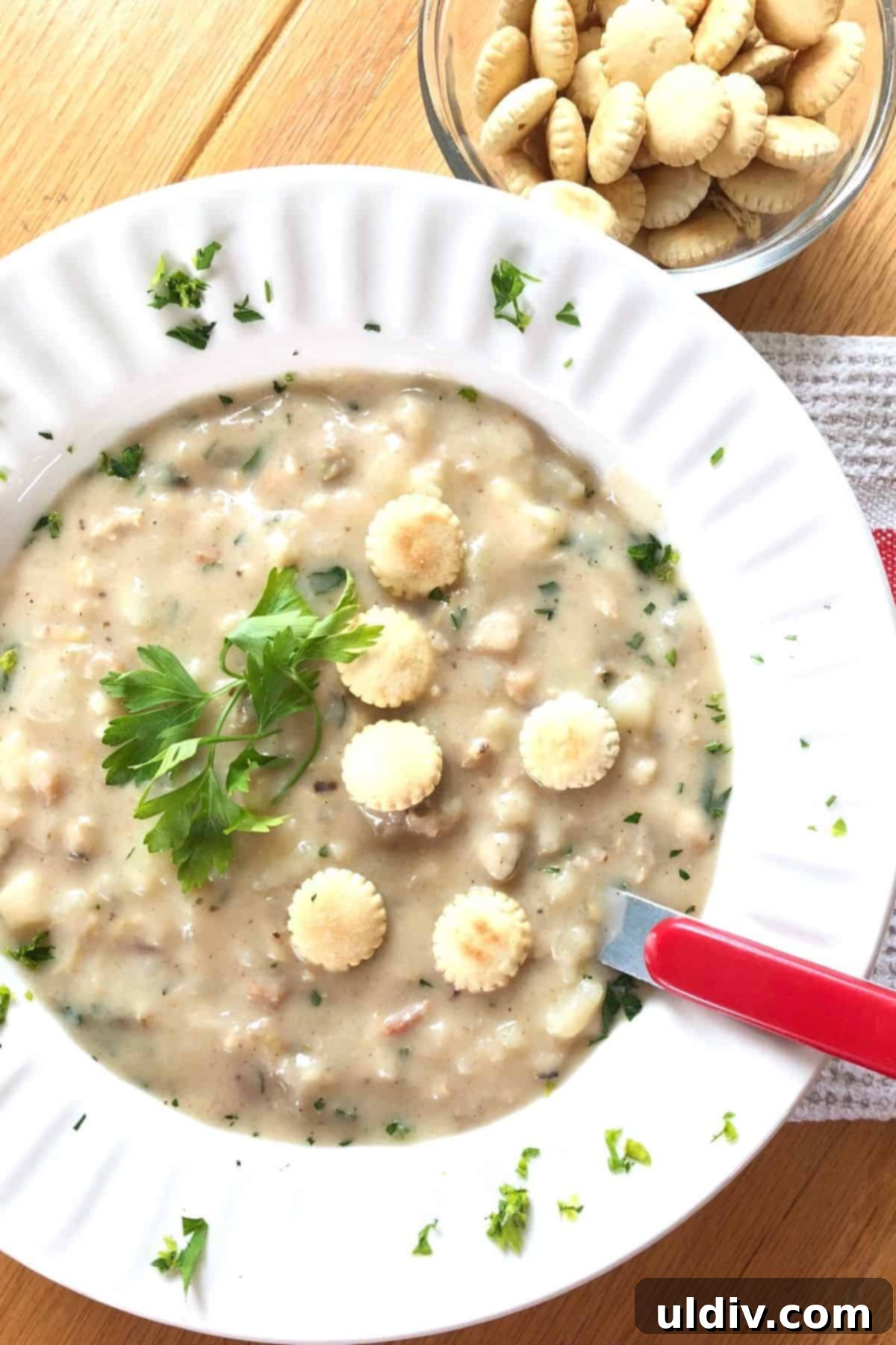 Classic Thick and Creamy New England Clam Chowder 3 Bowl of creamy New England clam chowder with oyster crackers, ready to eat.