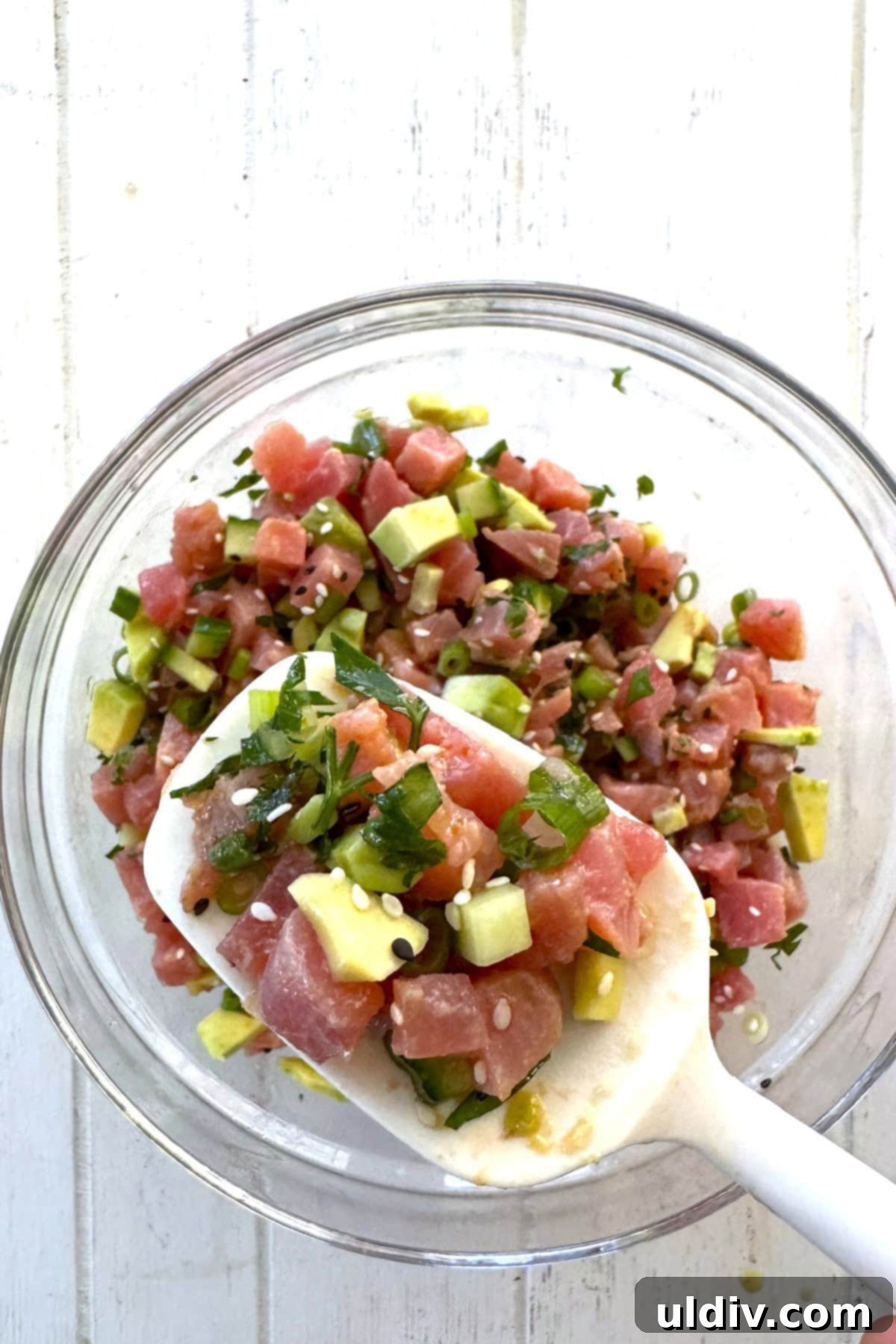 Fast and Fresh Tuna Ceviche 9 A spoon lifting a portion of raw tuna salad, showcasing its fresh ingredients and vibrant colors.