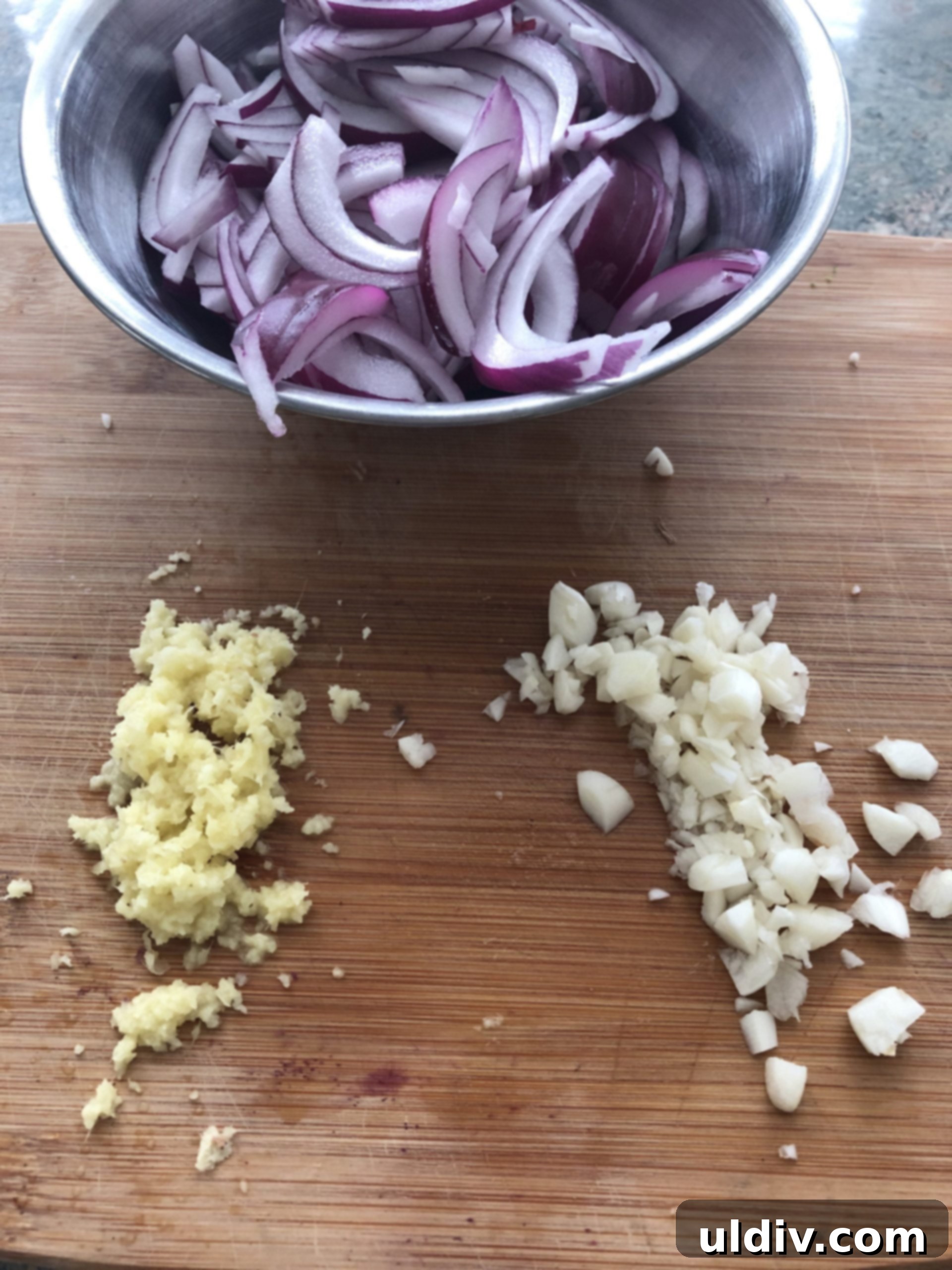 Velvety Butter Chicken with Fluffy Naan 5 Sliced red onions, chopped onions and minced garlic on a cutting board.