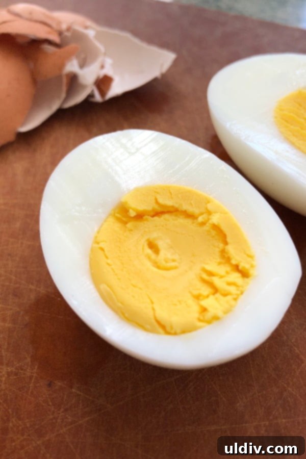 Timeless Deviled Egg Salad 3 Perfectly cooked hard-boiled eggs, sliced, showing a vibrant yellow yolk and firm white.