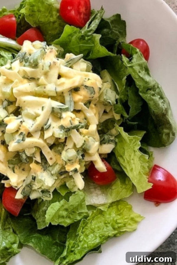 Timeless Deviled Egg Salad 4 Plate of chunky deviled egg salad served over fresh greens with cherry tomatoes on the side.