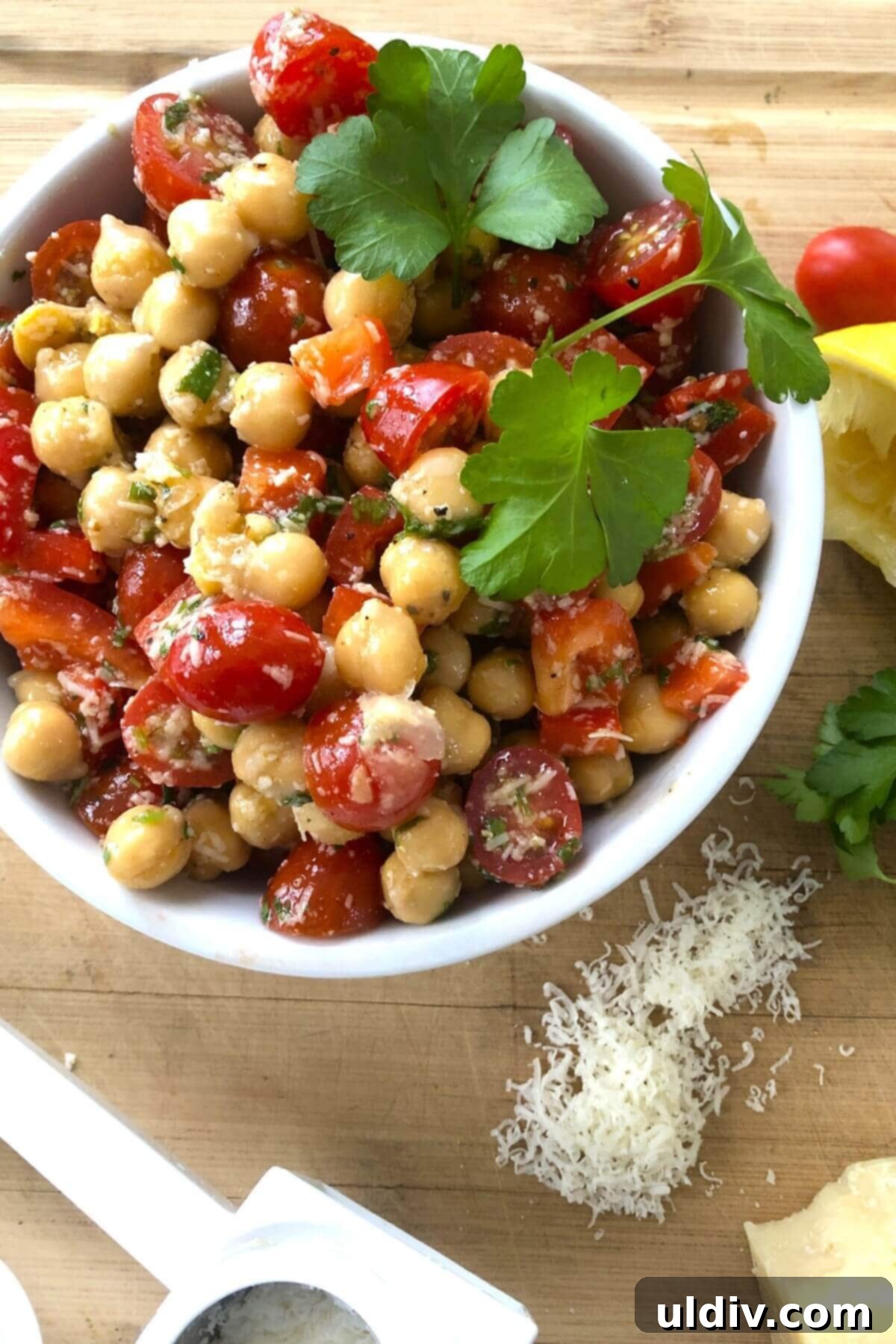Mediterranean Chickpea Tomato Salad with Zesty Herb Dressing 2 chickpeas salad in a white bowl. A delicious and hearty chickpea salad with a fresh herb vinaigrette, cherry tomatoes and Parmesan cheese compliments any meal.