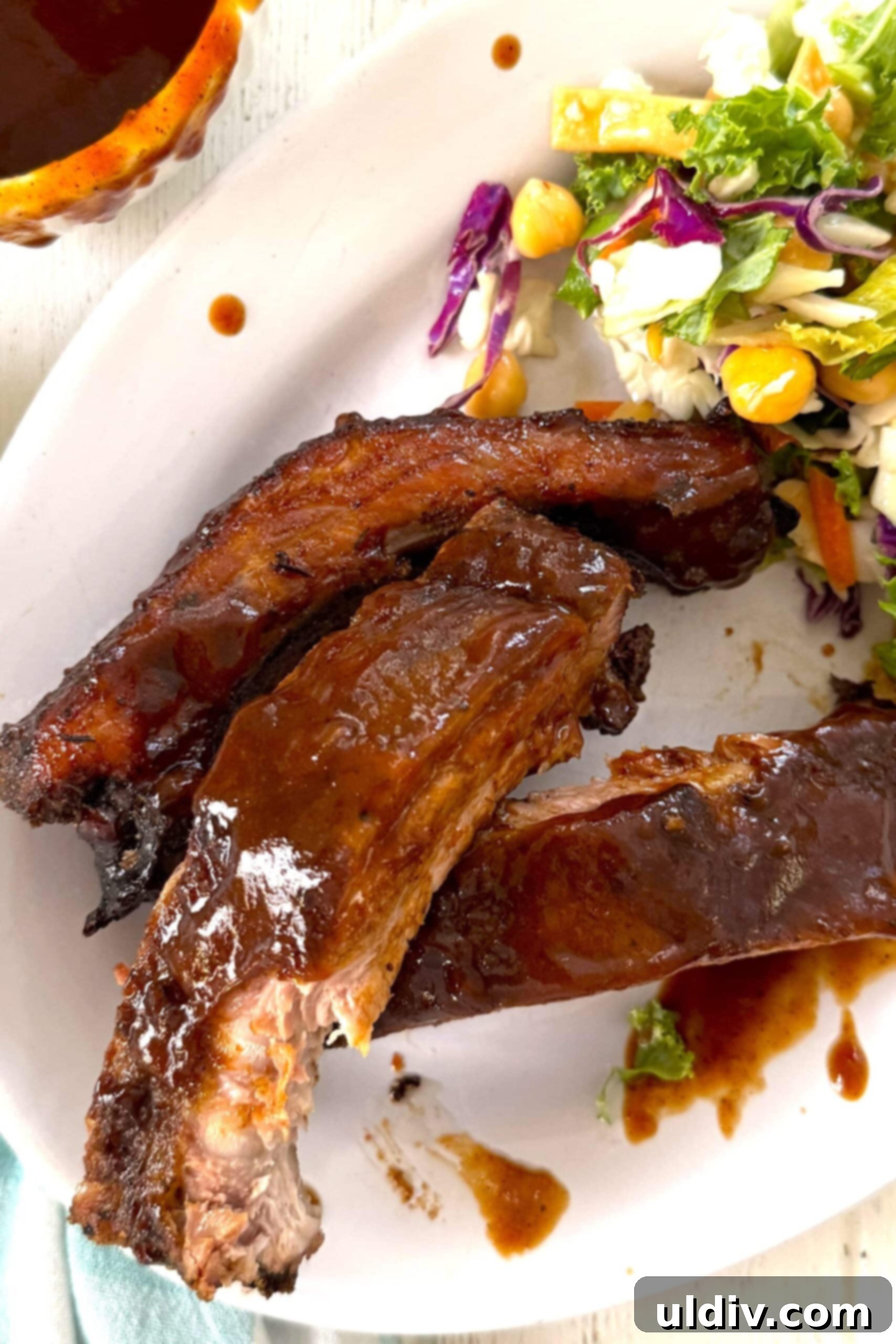Meltingly Tender Baked Baby Back Ribs 2 3 baked baby back ribs on a plate with salad.