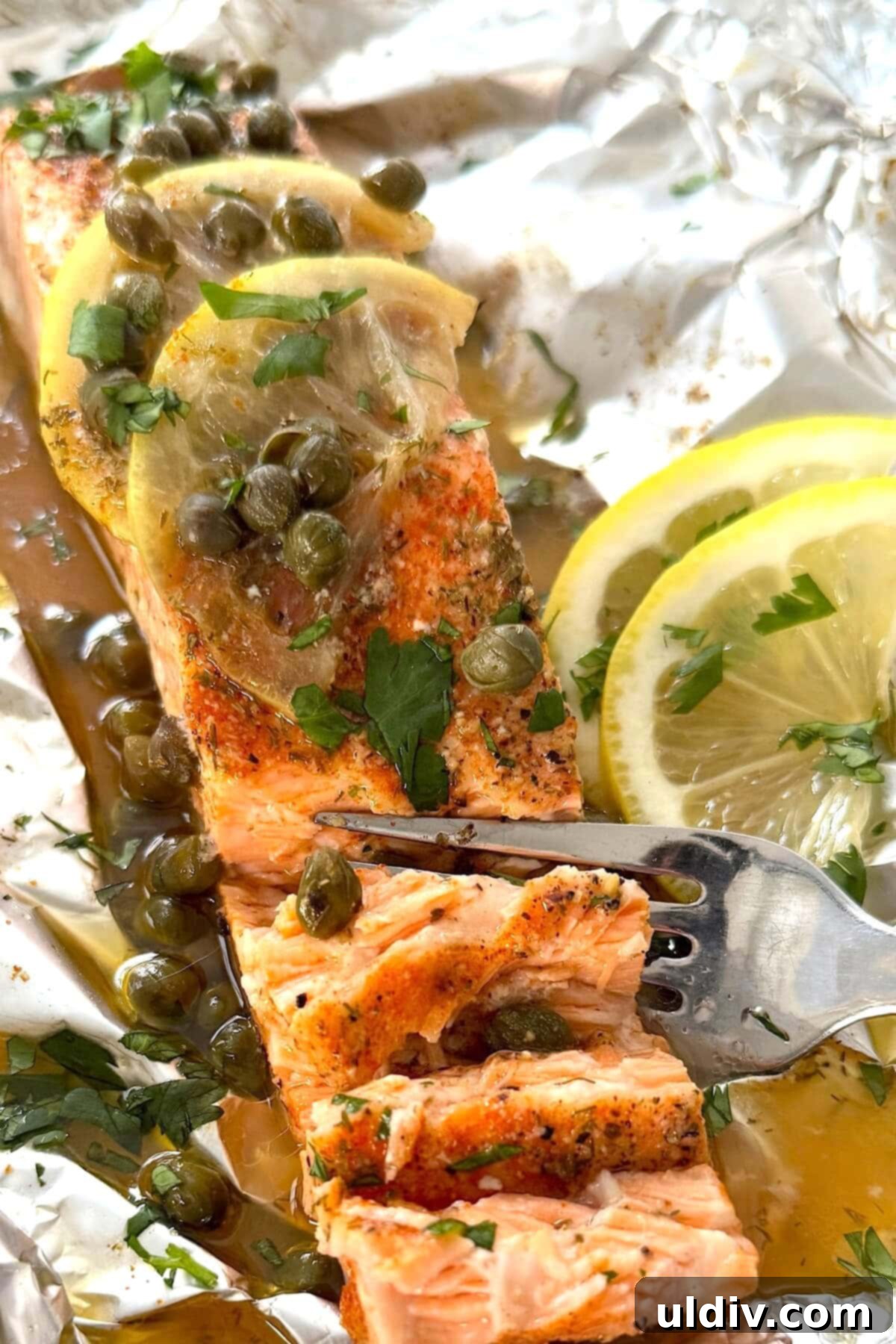 Simple Healthy Foil-Baked Salmon 2 Perfectly baked salmon in foil, garnished with fresh lemon, briny capers, and a rich buttery wine sauce, ready to be served.