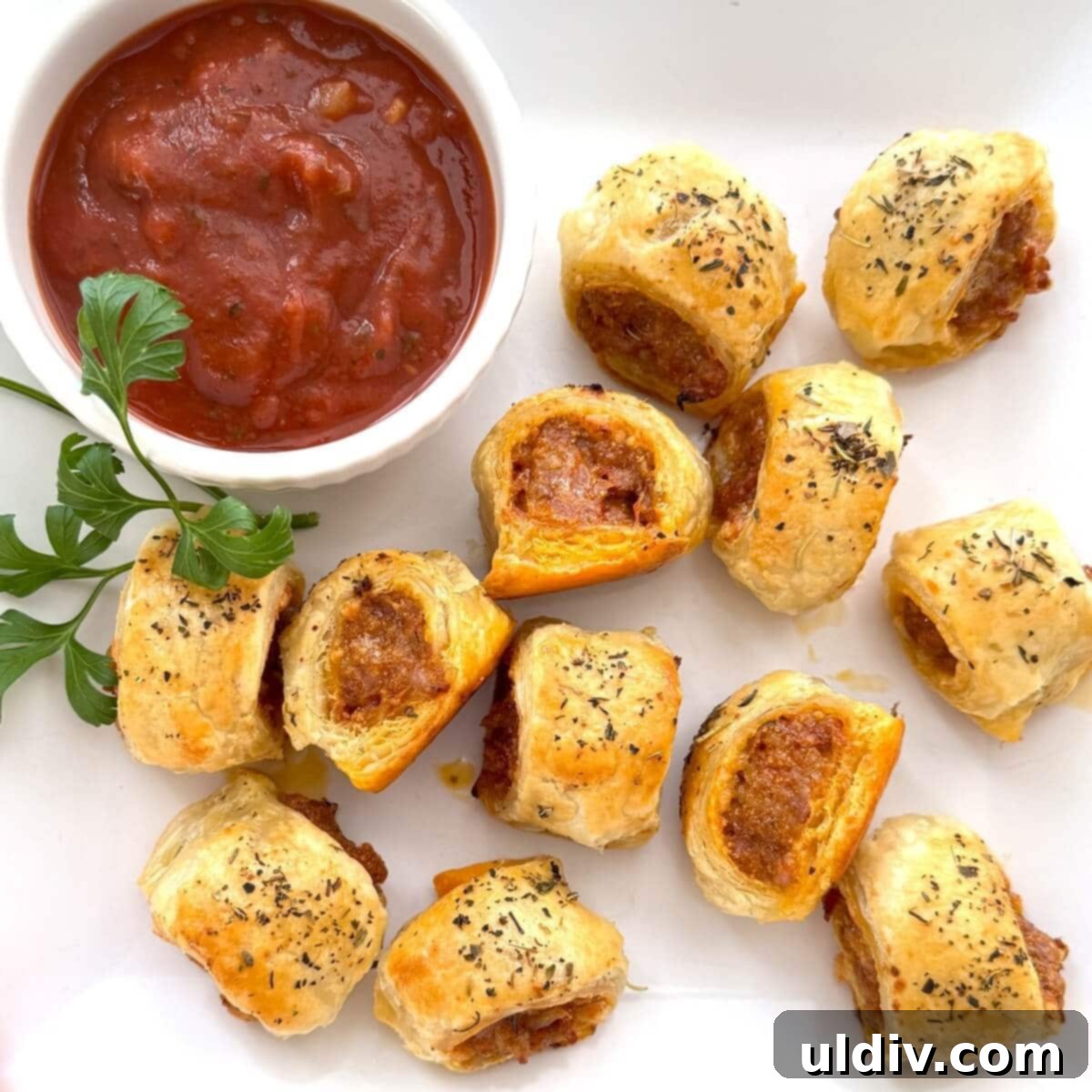 Homemade Pizza Sausage Rolls 12 Homemade sausage rolls served on a platter with a bowl of marinara sauce for dipping.