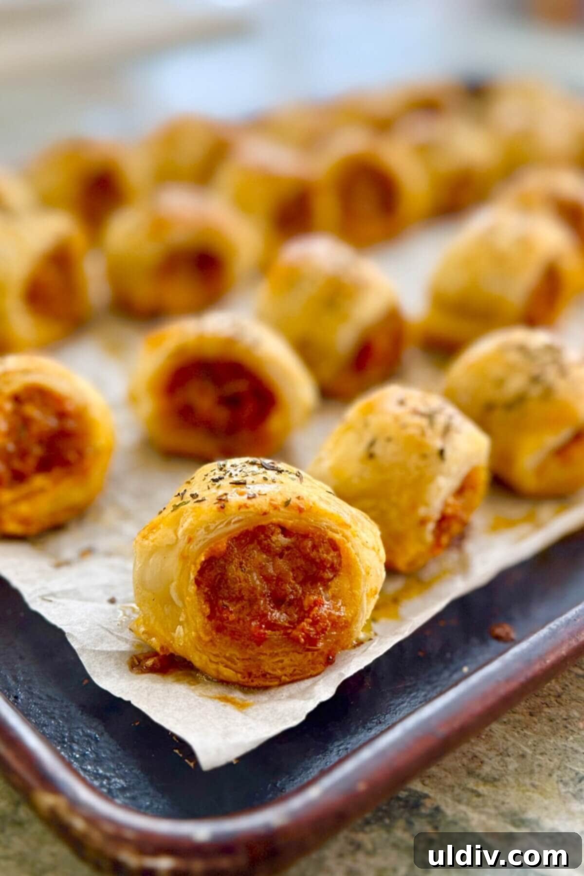 Homemade Pizza Sausage Rolls 14 Puff pastry rolls with Italian sausage filling, unbaked and arranged neatly on a baking sheet.